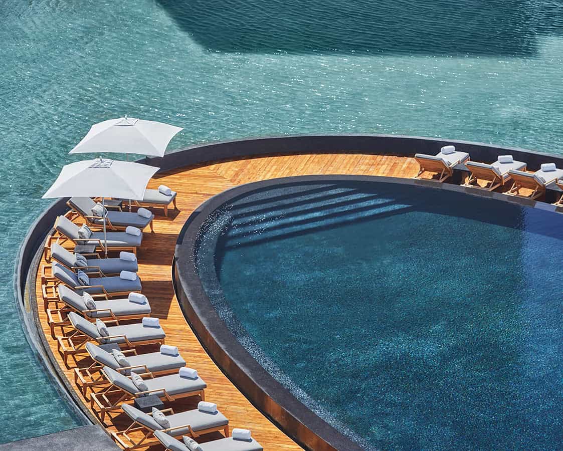 rounded hotel pools with wood walkways and white lounge chairs