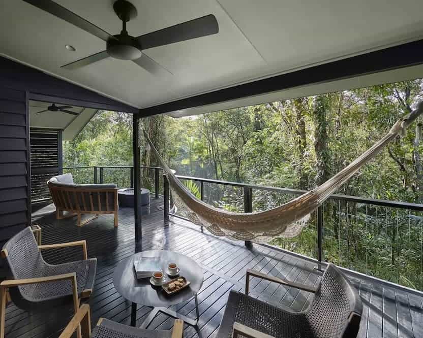 balcony with chairs and hammock overlooking a green rainforest