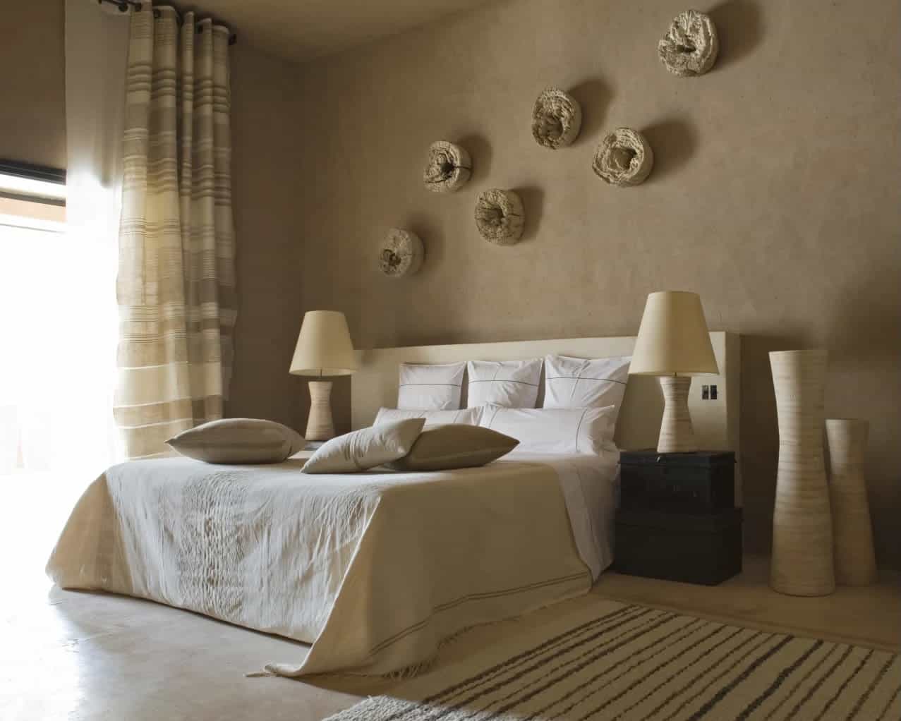 earth tone rustic room with bed, nightstands with lamps, and wall artwork of a hotel room