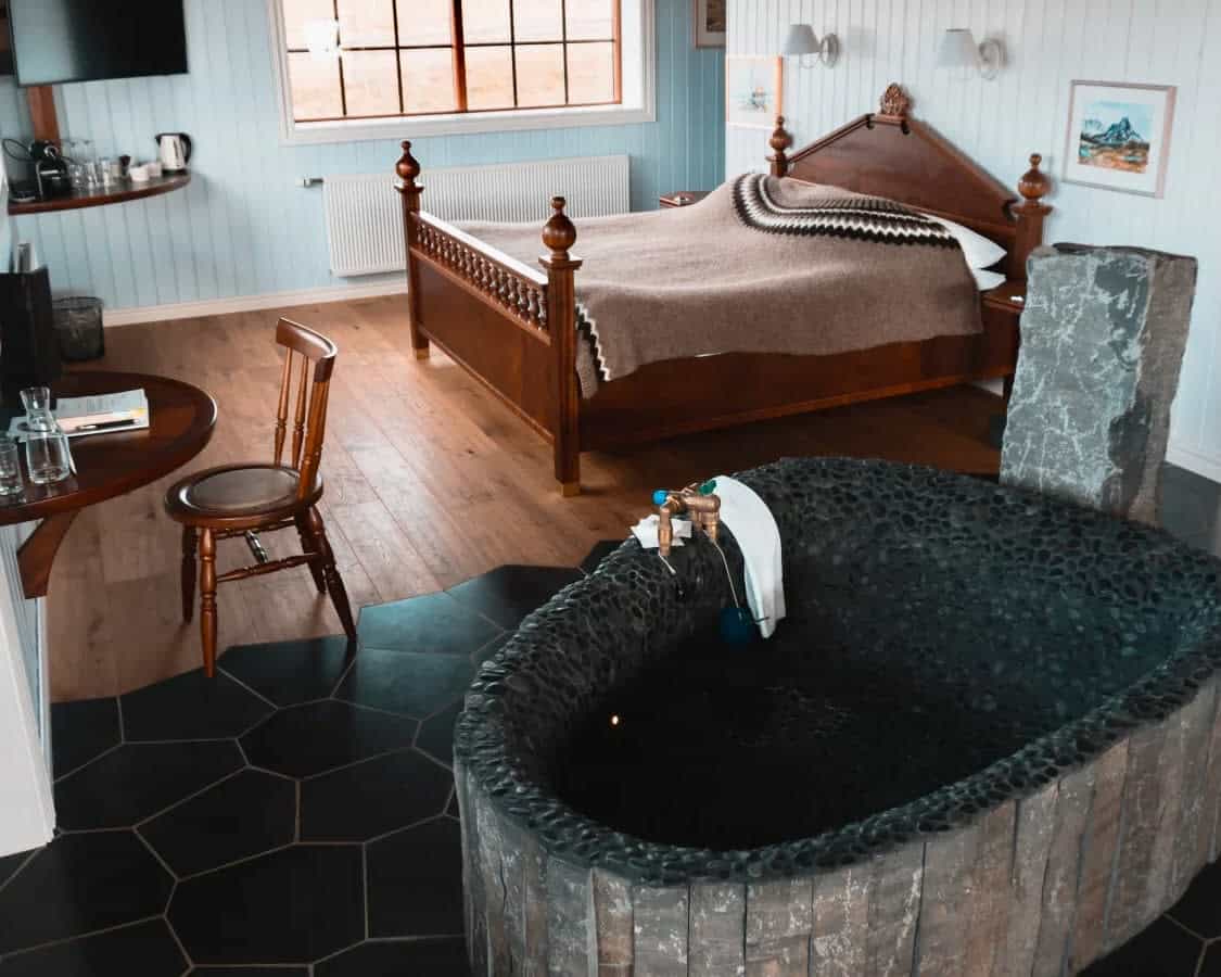 hotel room with wood floors and furniture, and a black stone bathtub