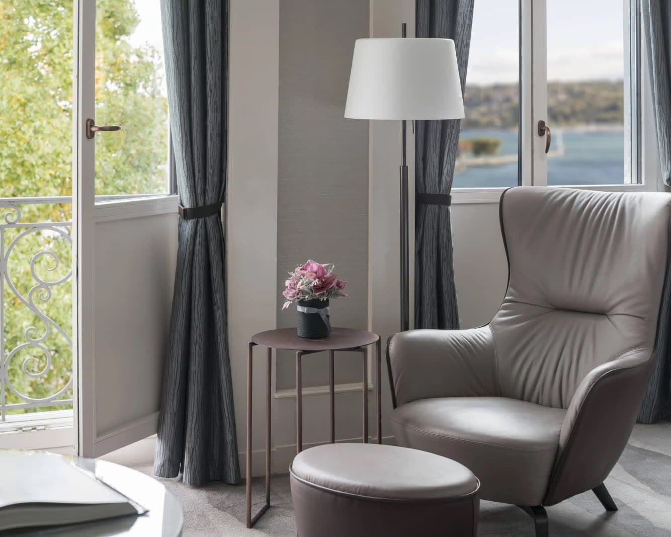 grey chair and ottoman next to a window and open balcony door