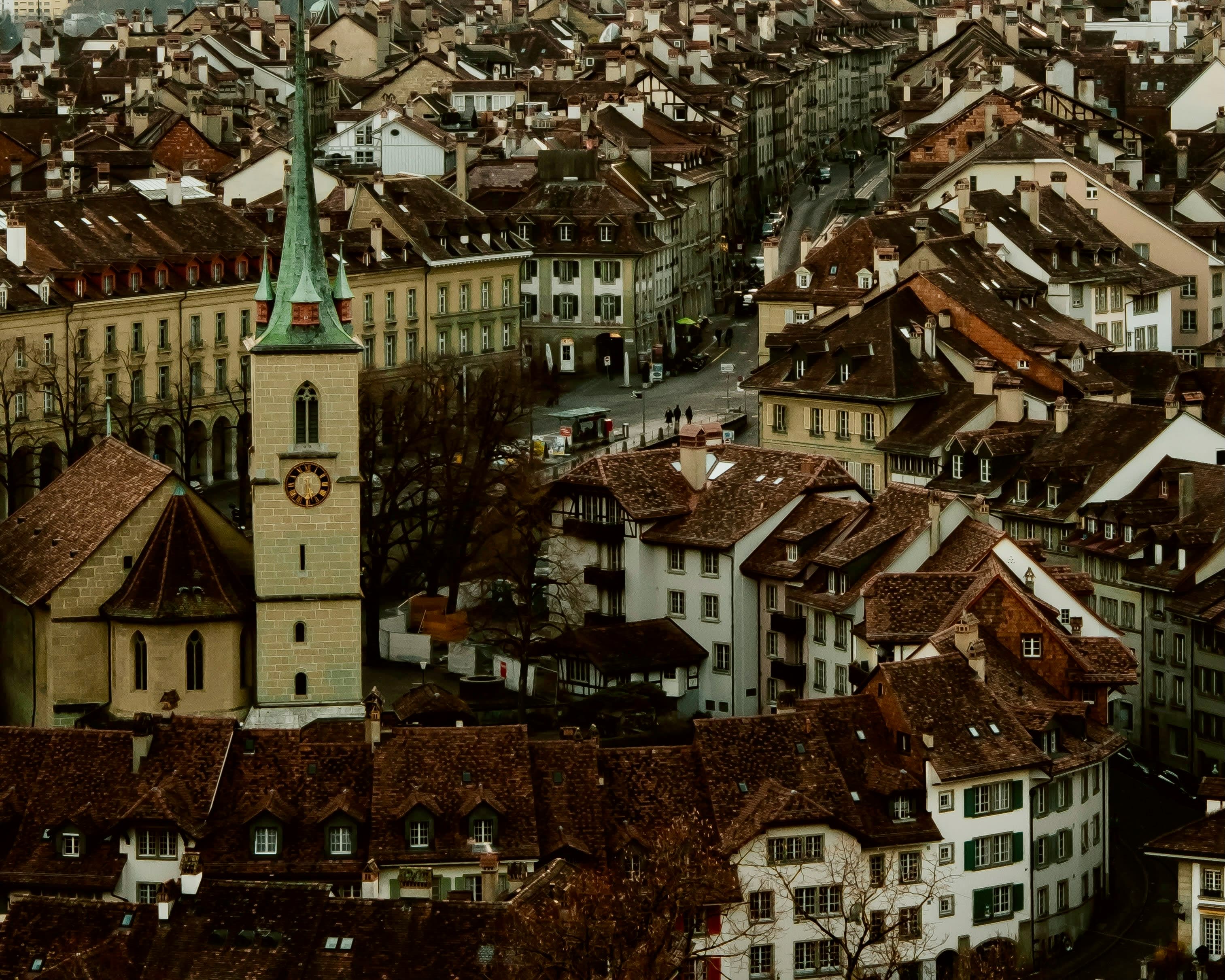 cityscape of brown rooftops, white buildings and green church steeple.