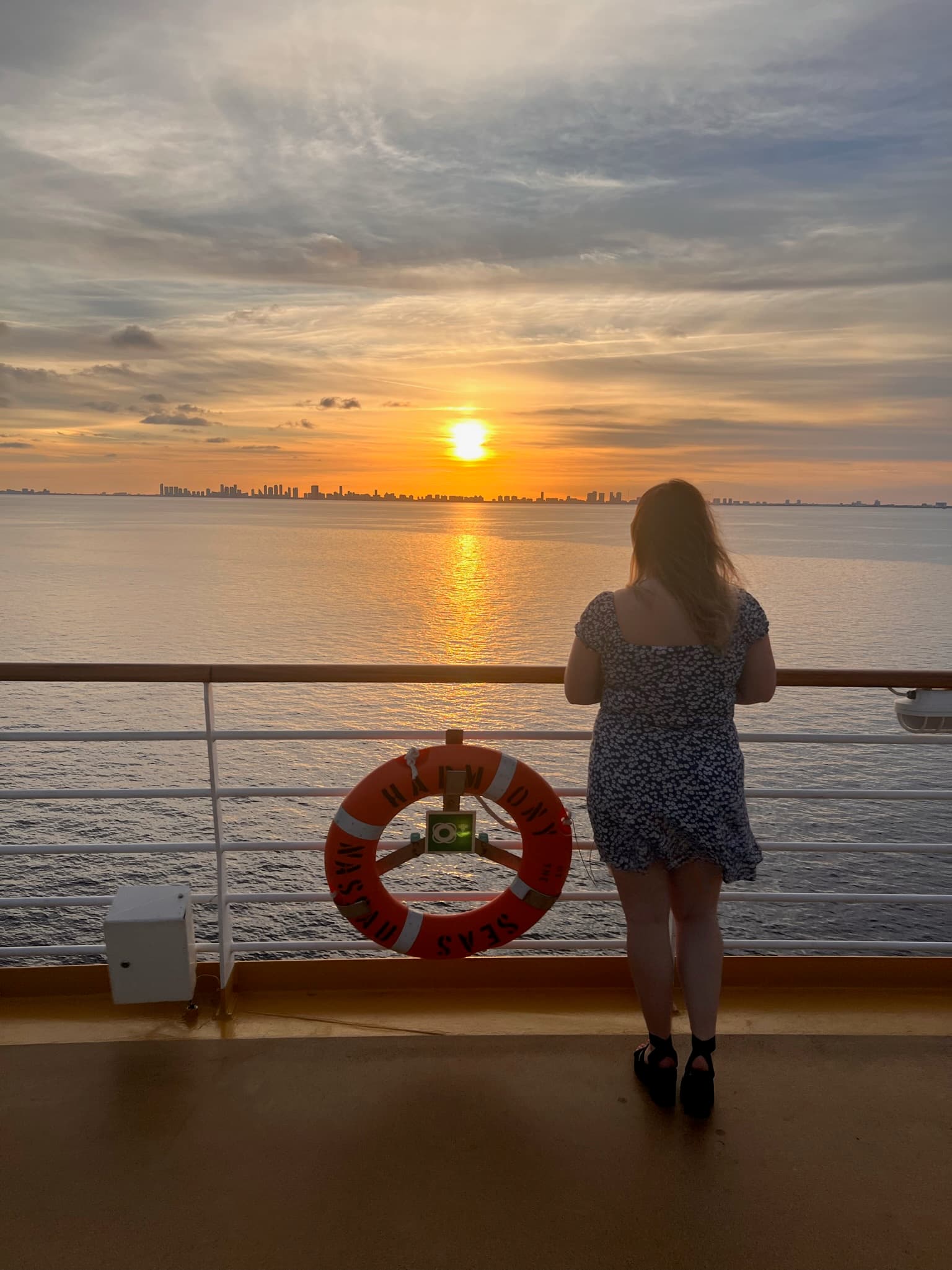 Advisor standing on the deck of a cruise ship with a sunset in the distance.