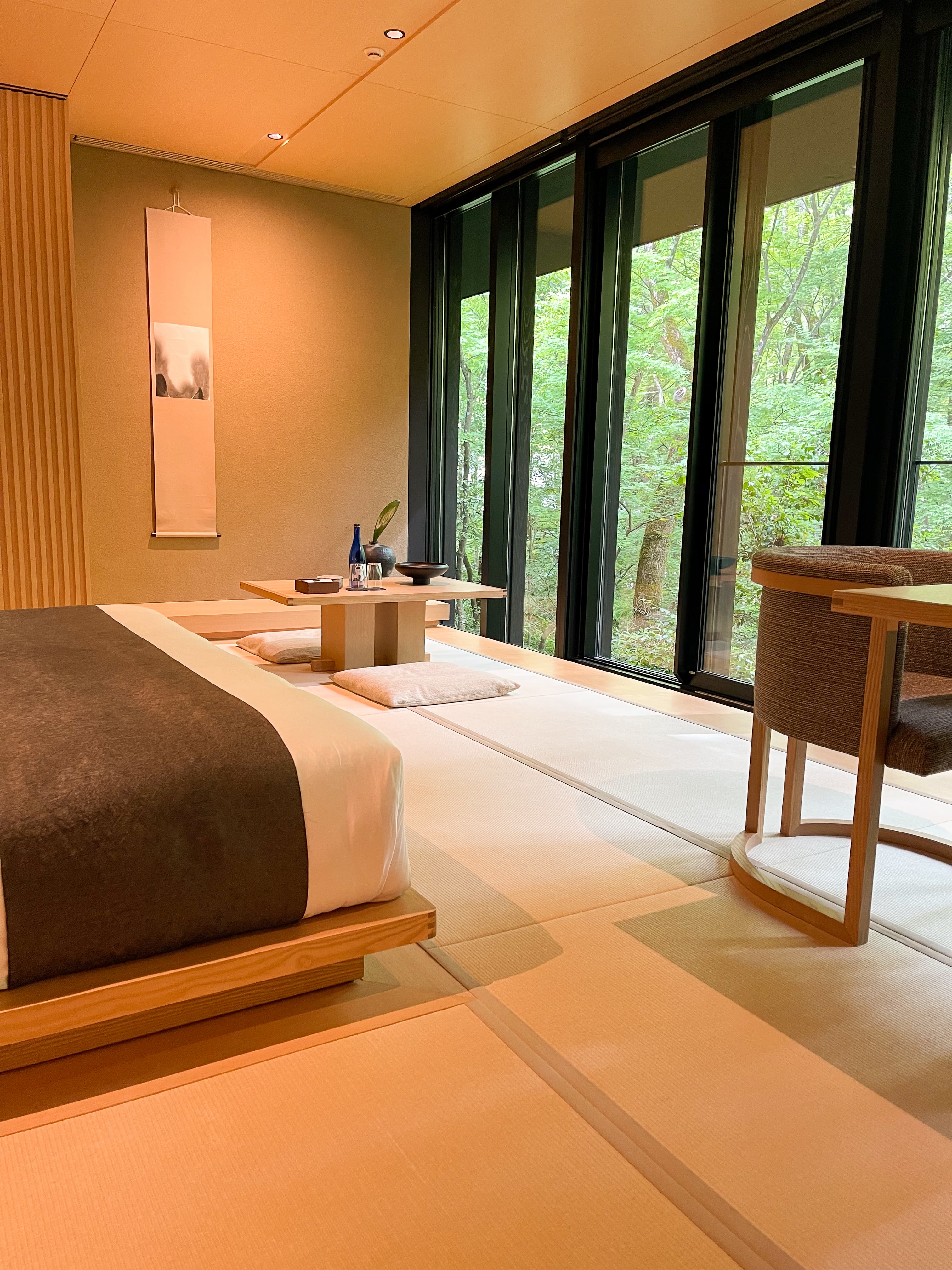 View of a zen room with floor to ceiling windows looking out to a garden at the Aman Tokyo