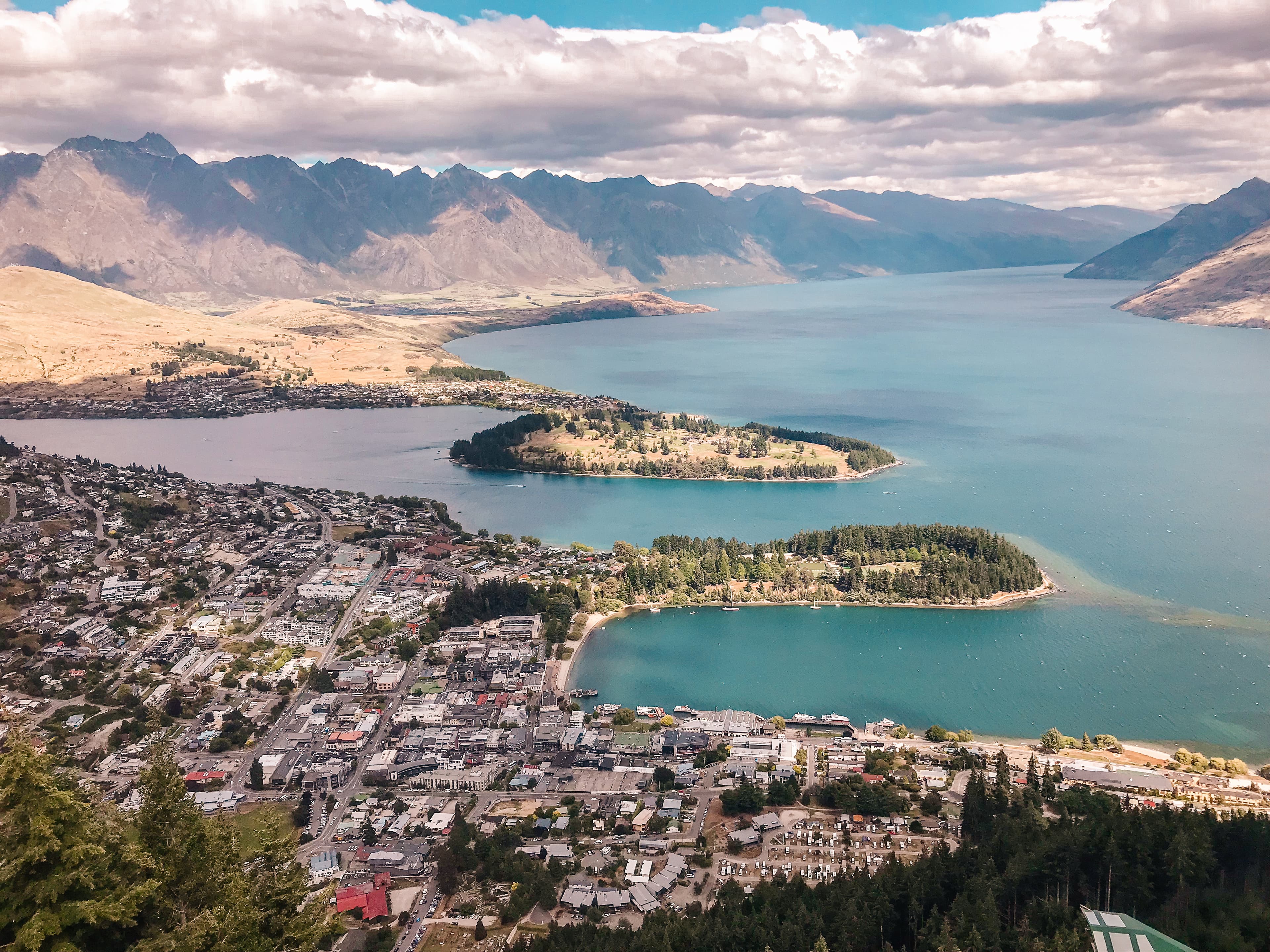 Beautiful aerial view of a coastal city and bright blue water with a large mountain range in the distance