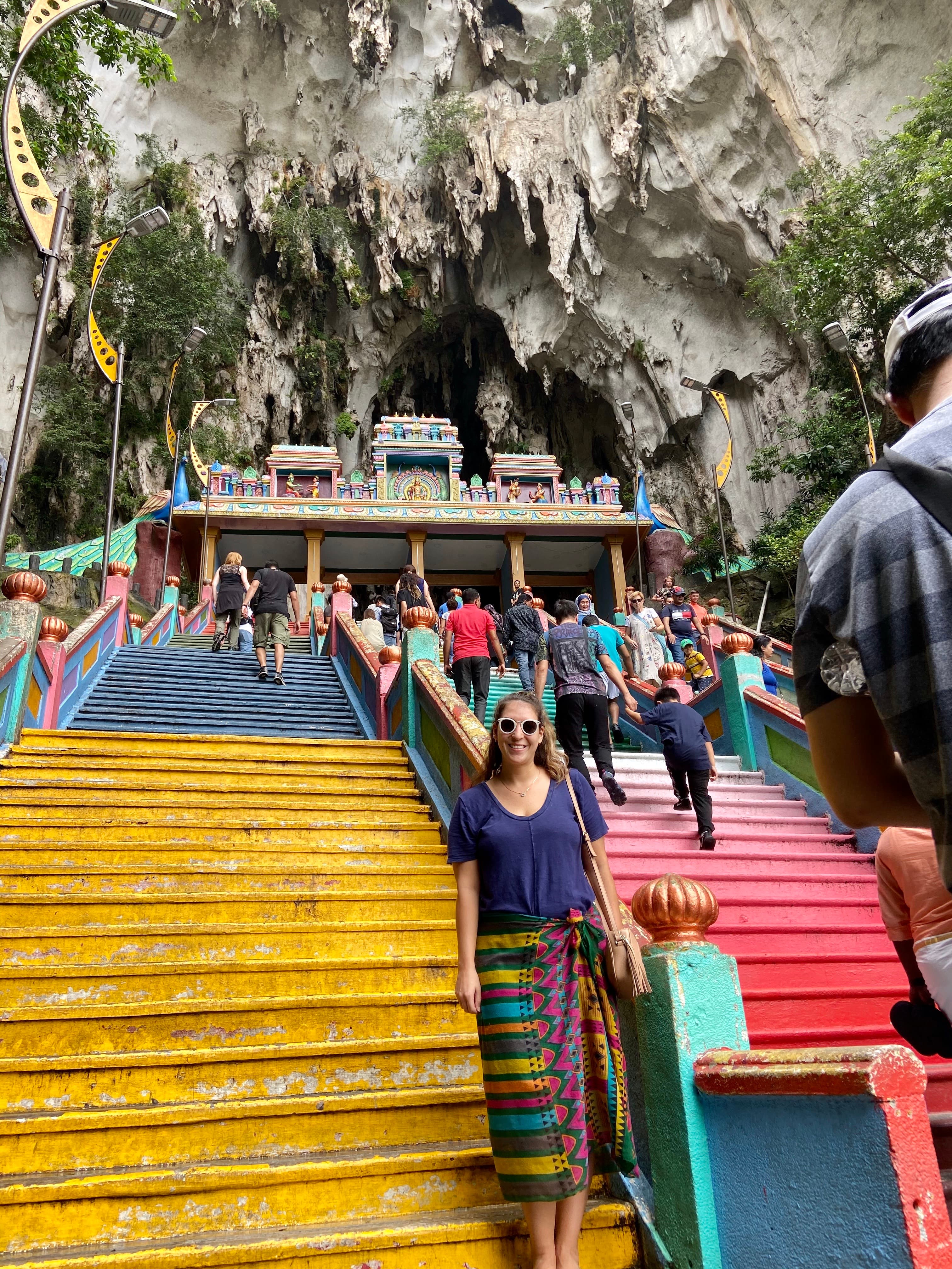 Lyndsay wearing a colorful skirt and posing on a yellow staircase leading up to a shrine