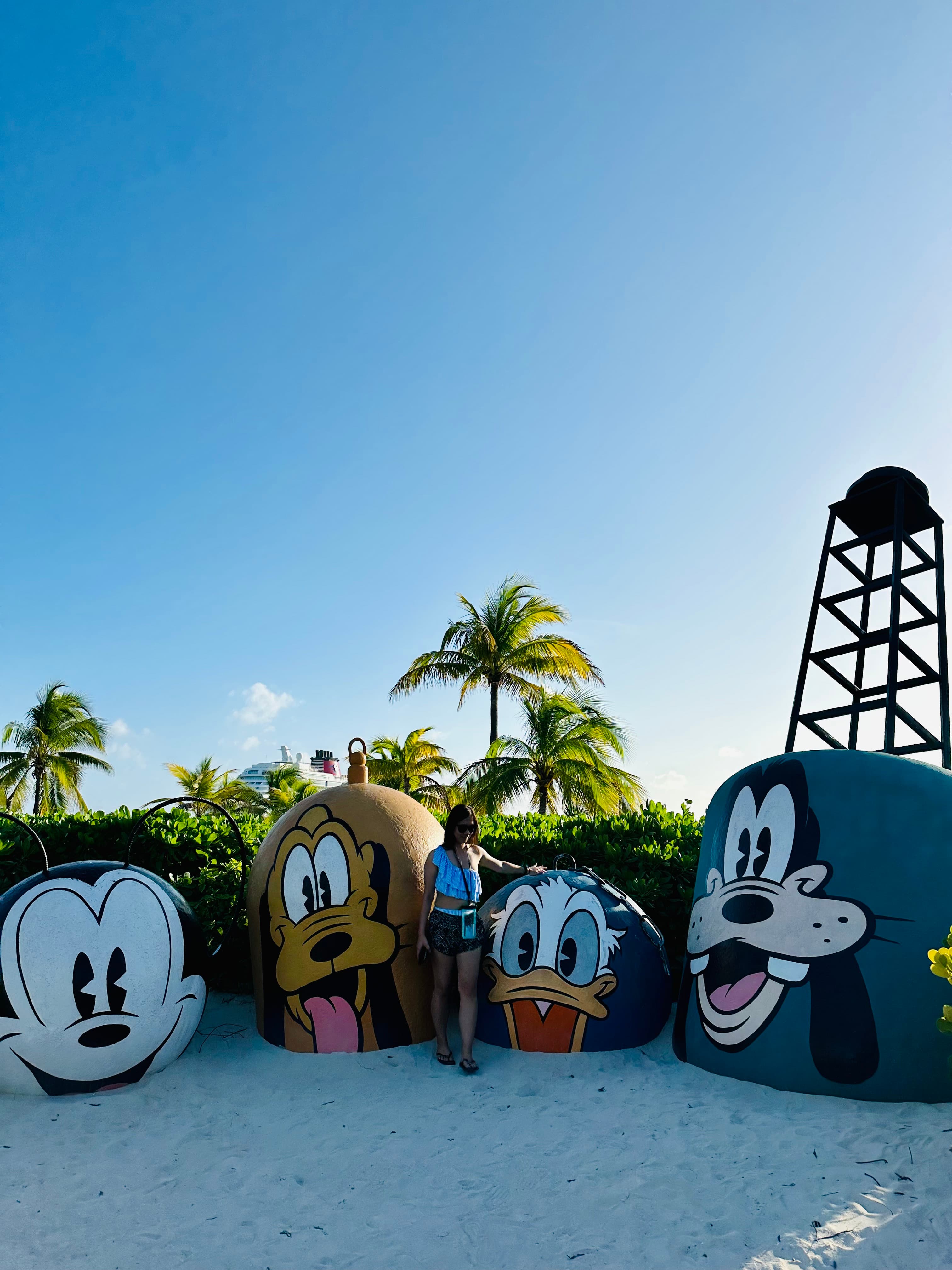 Advisor standing in front of large Disney character statues with palm trees in the distance at dusk.