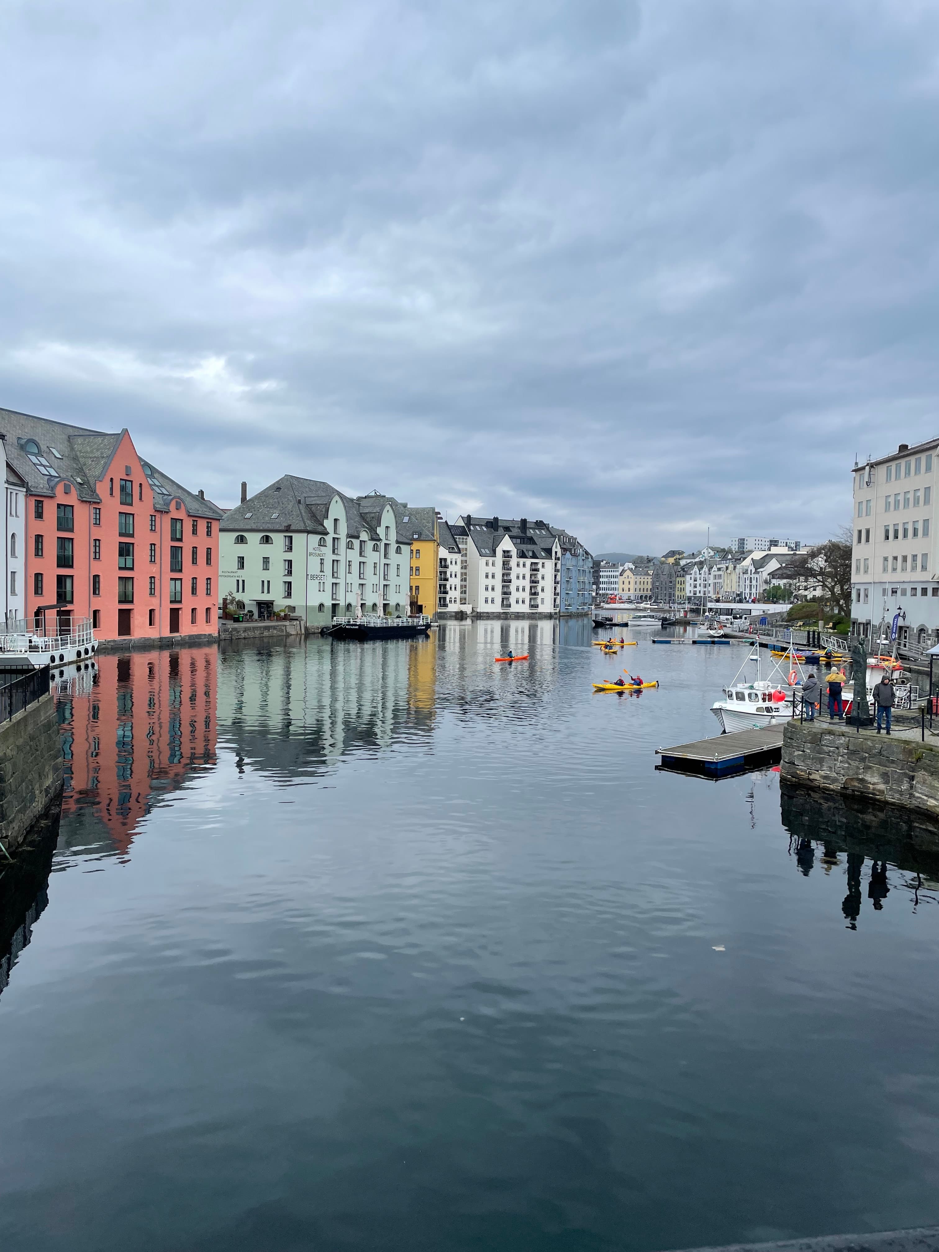 A water way with colorful buildings, boats and a concrete dock.