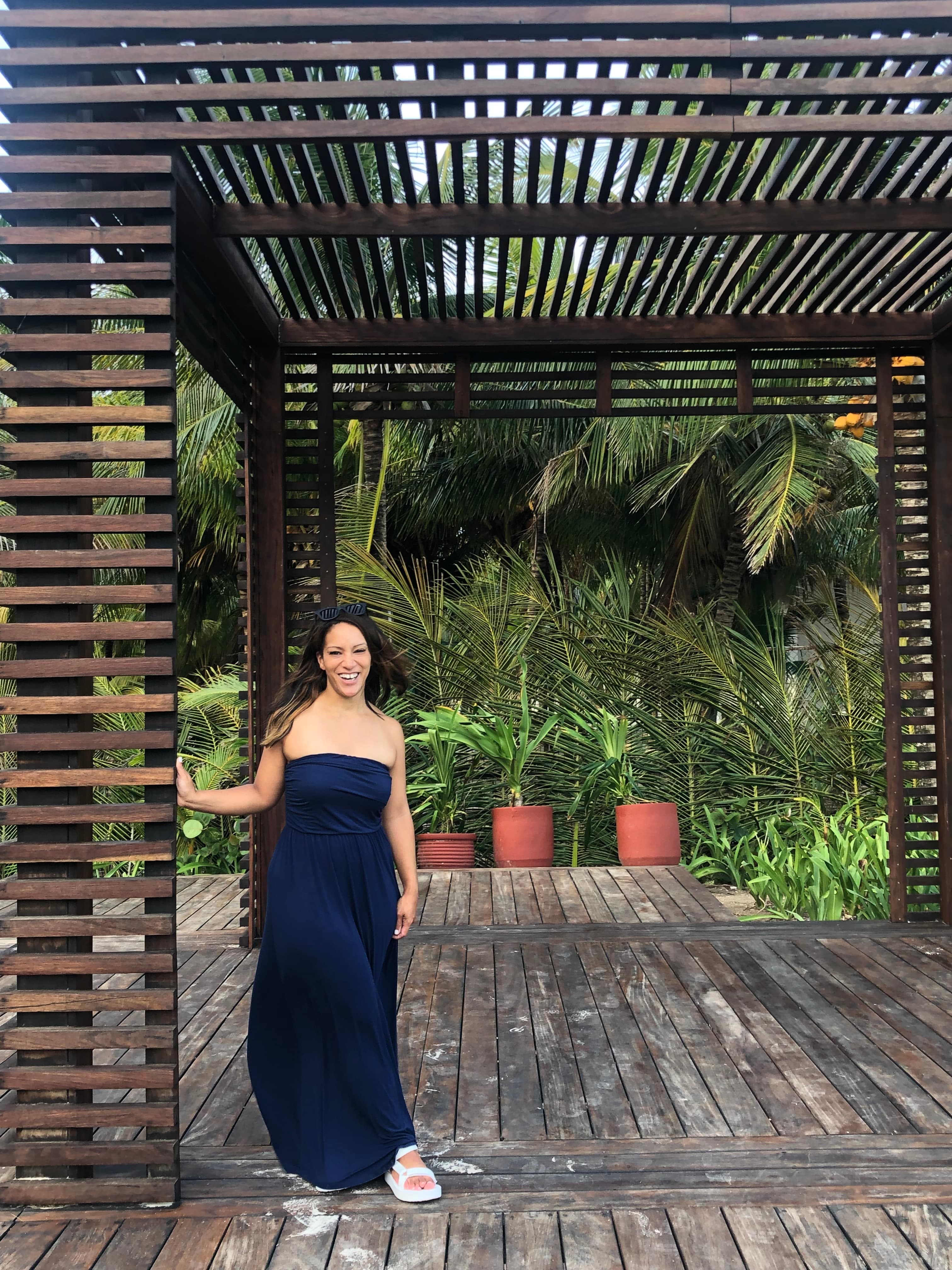 Advisor posing with foliage in the distance on a sunny day.