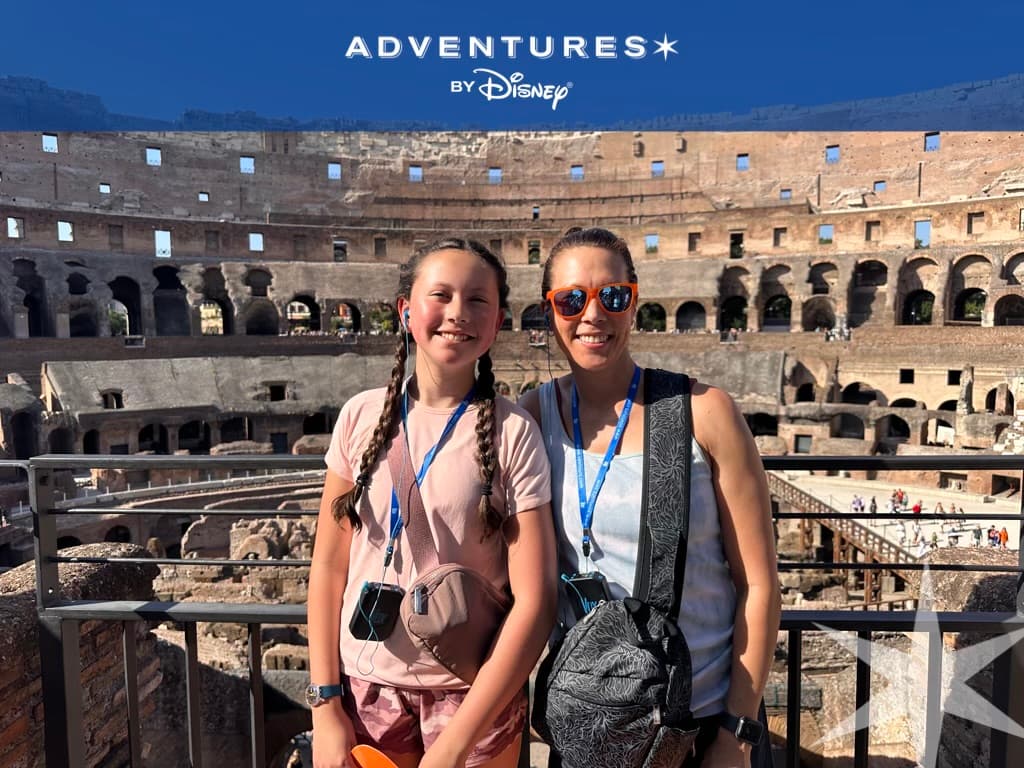 Two people posing outside of an ancient colosseum.