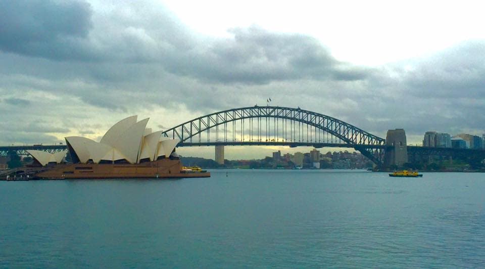 A view of the Sydney Opera House and bridge on a cloudy day at sunset