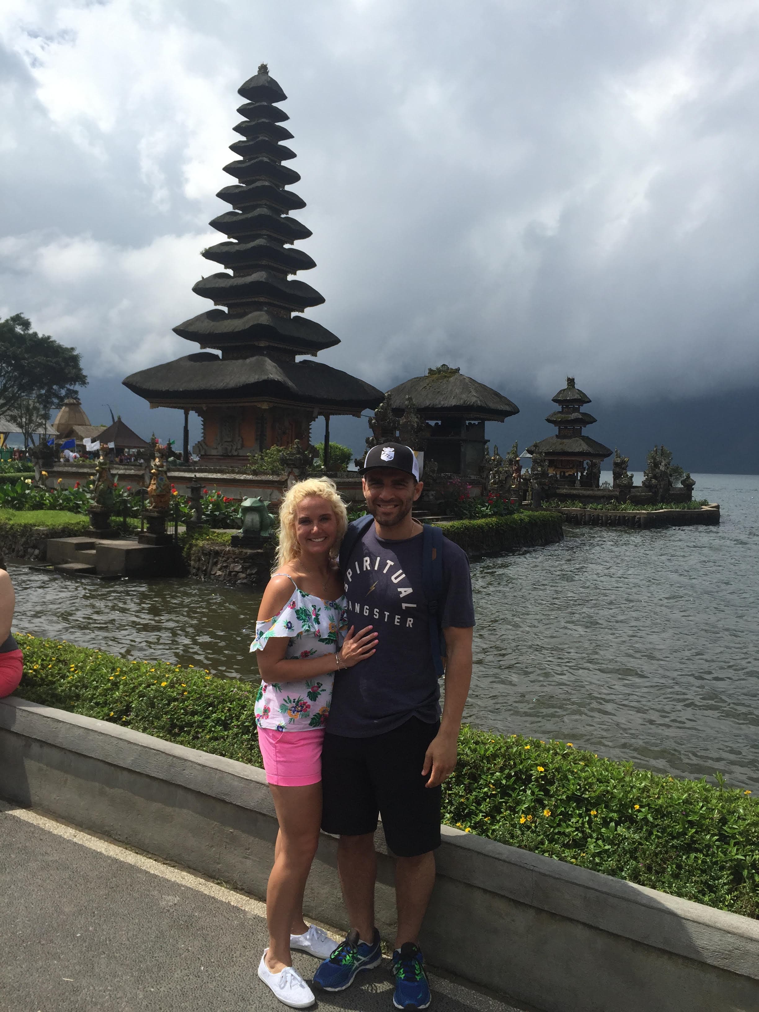 Travel advisor Meg and male companion standing by a body of water with a tall Asian-style temple in the background