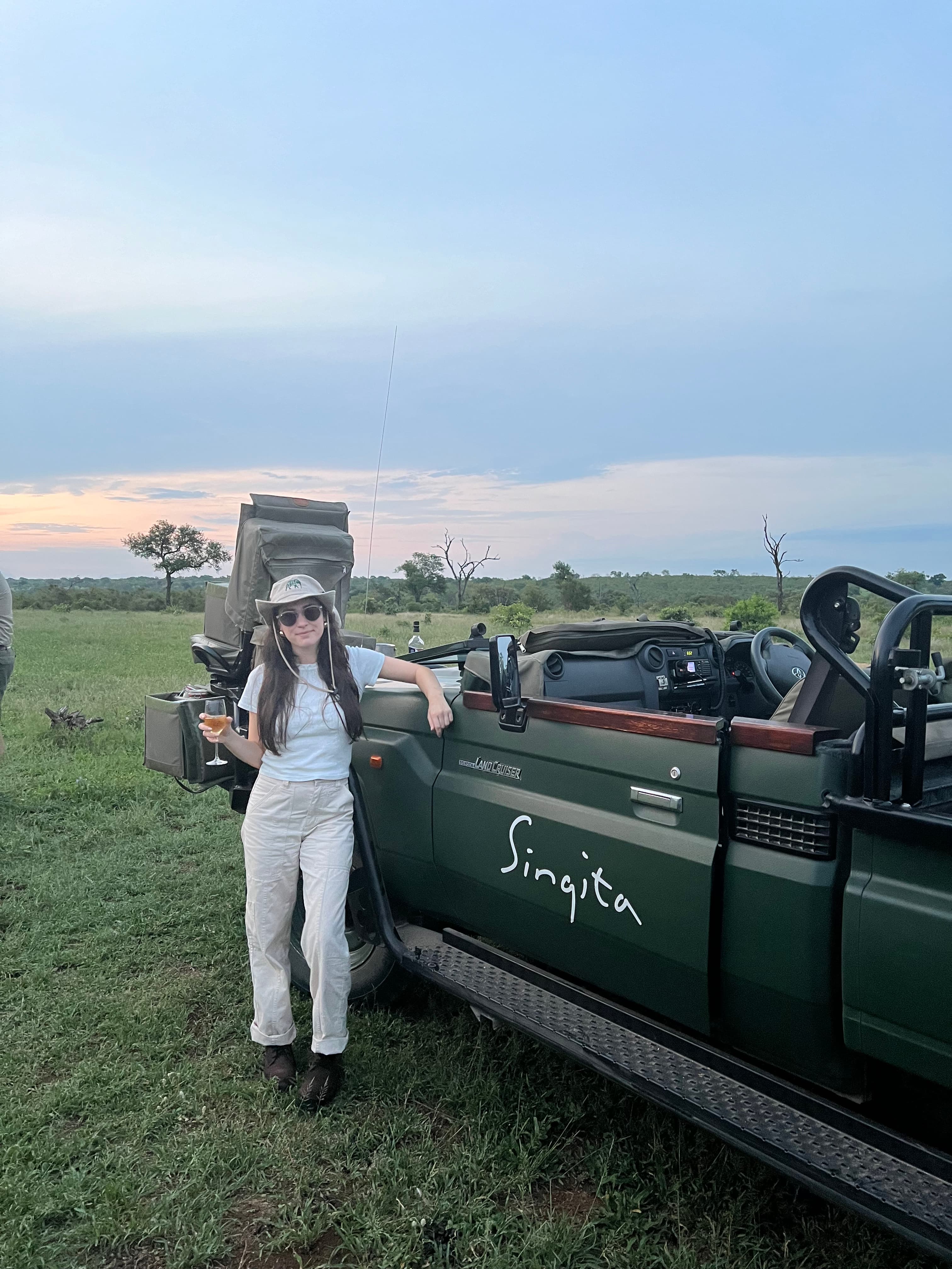 Travel advisor Spencer standing in front of a green open-top vehicle in a grassy area