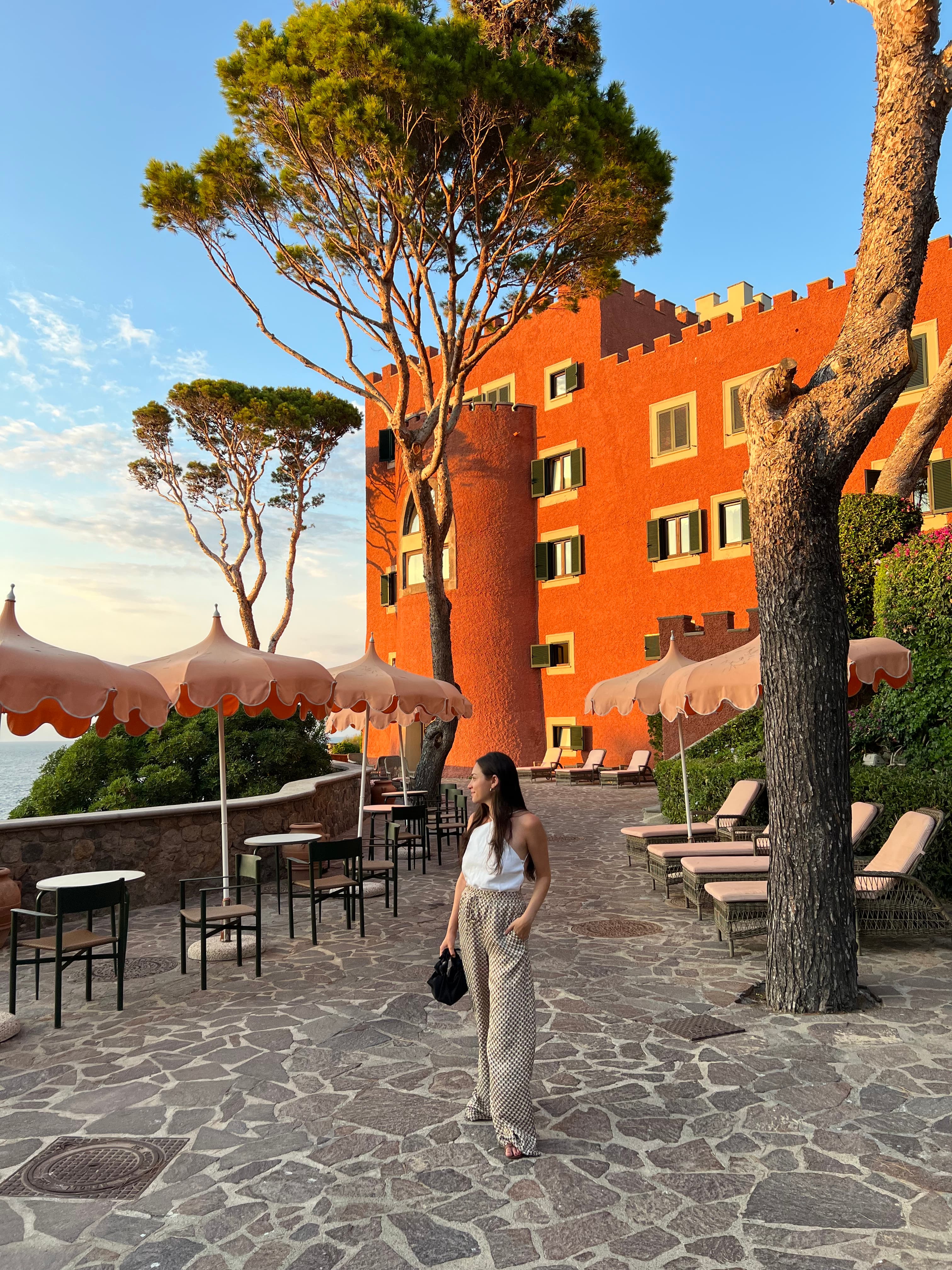 Travel advisor Spencer standing on a stone esplanade in front of an orange building and a seating area with orange parasols.