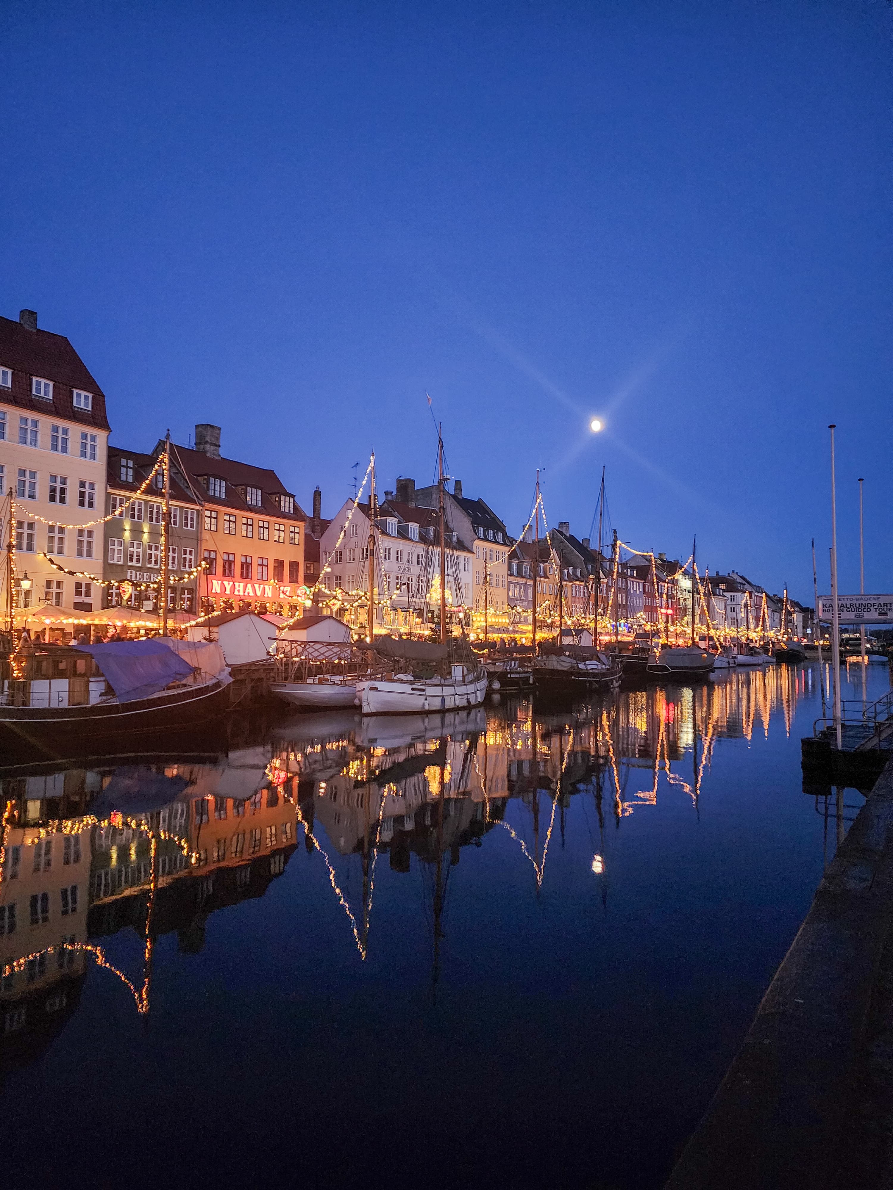 A view of a beautiful waterway at night time with bright lights and a row of homes.