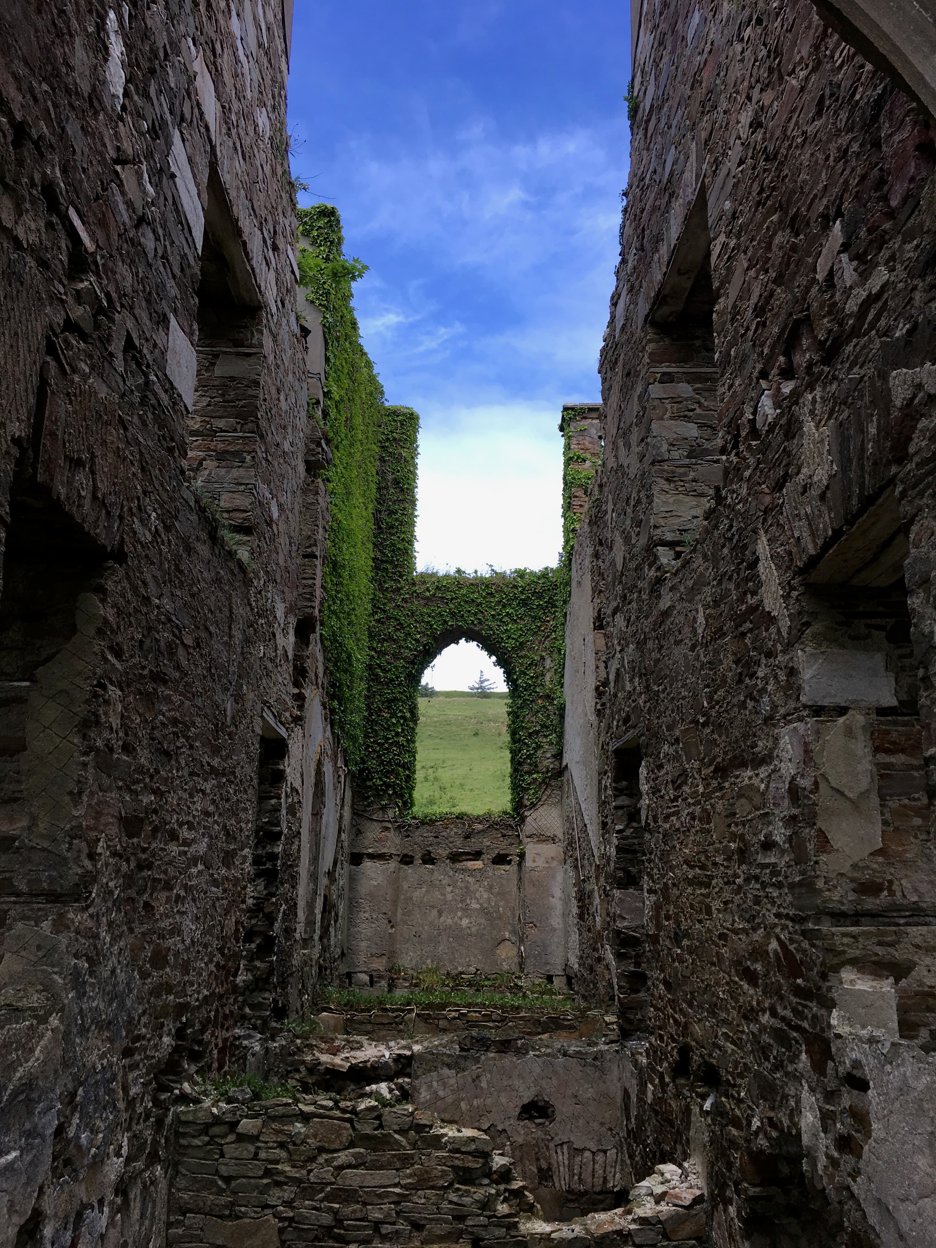 The interior of ancient stone ruins with a green arch.