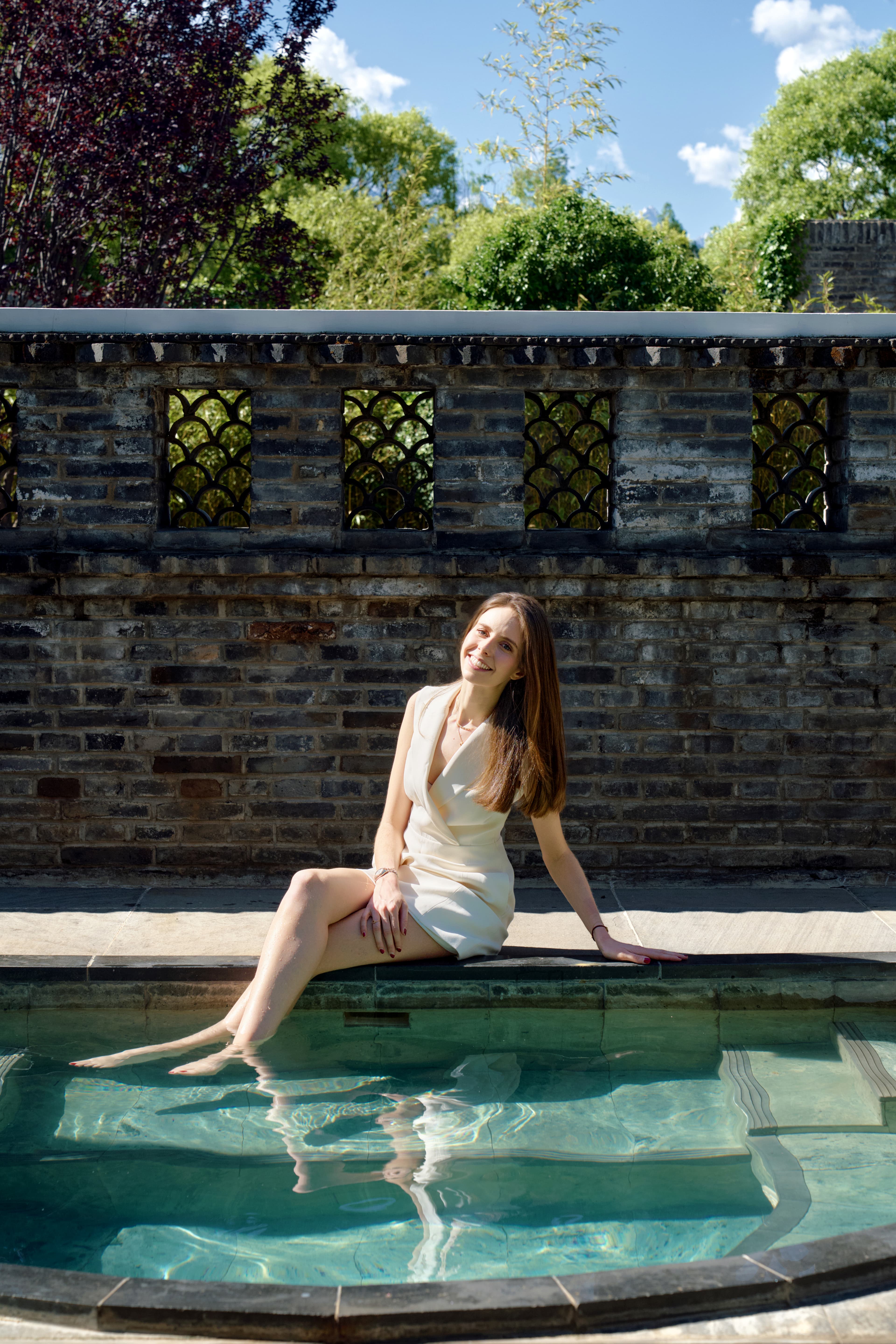 Advisor sitting in a pool on a sunny day with a brick wall and foliage in the distance.