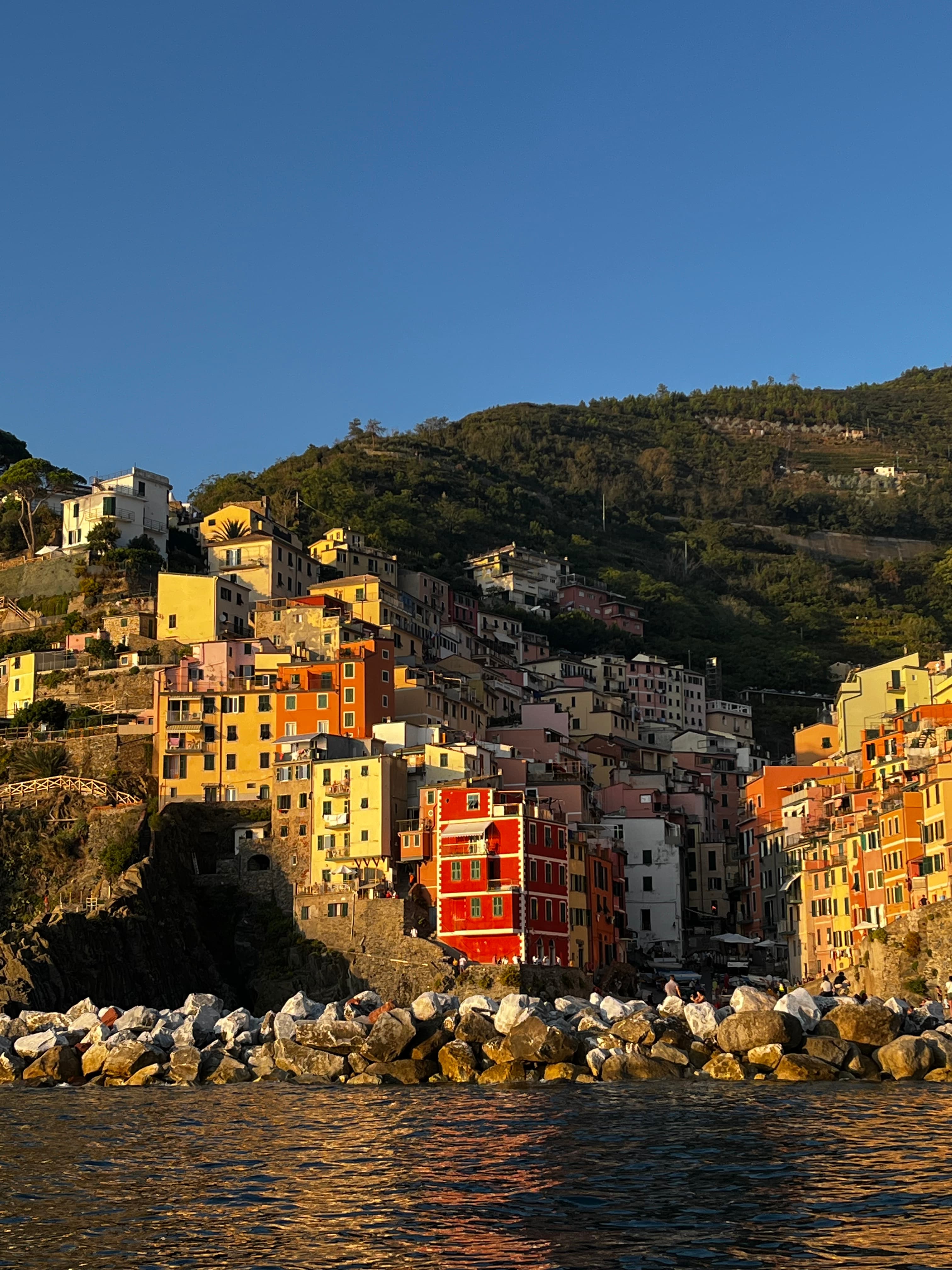 A view of colorful houses by a coastline, built into the coast's mountain on a sunny day.