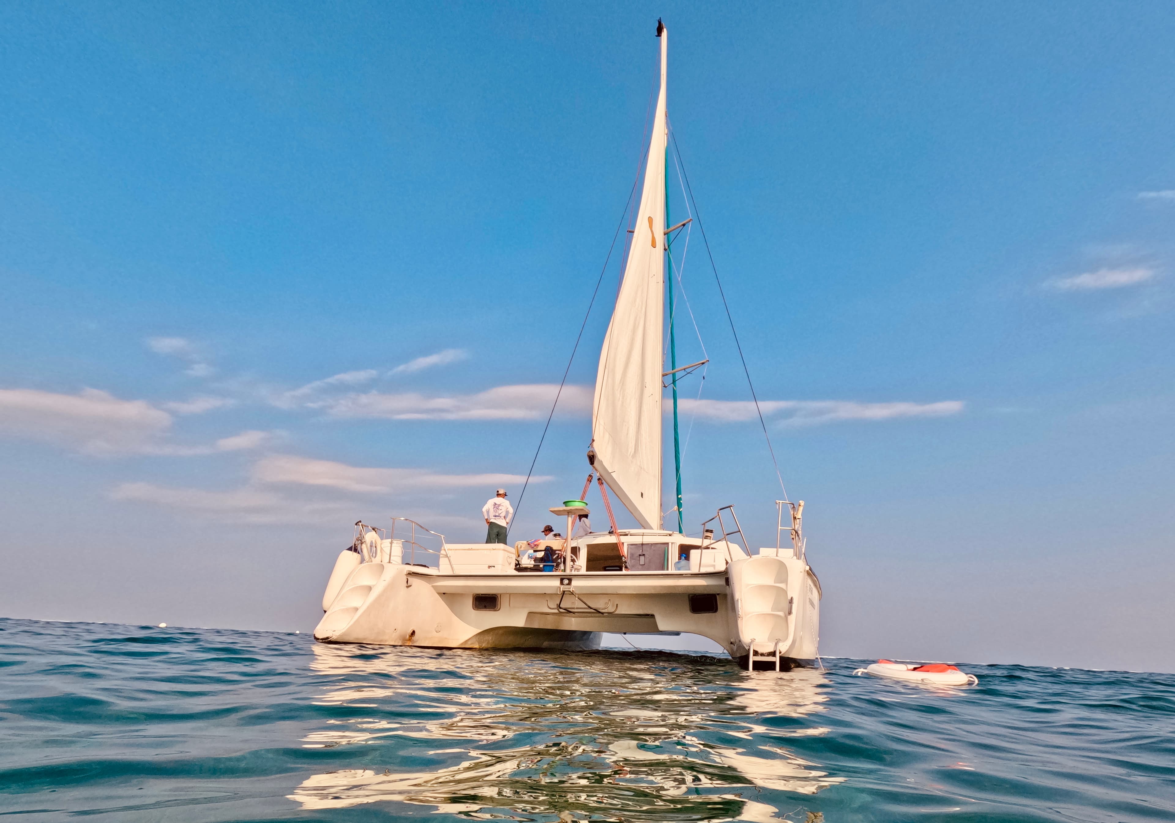 A view of a sailboat in the ocean on a beautiful sunny day with clear skies.