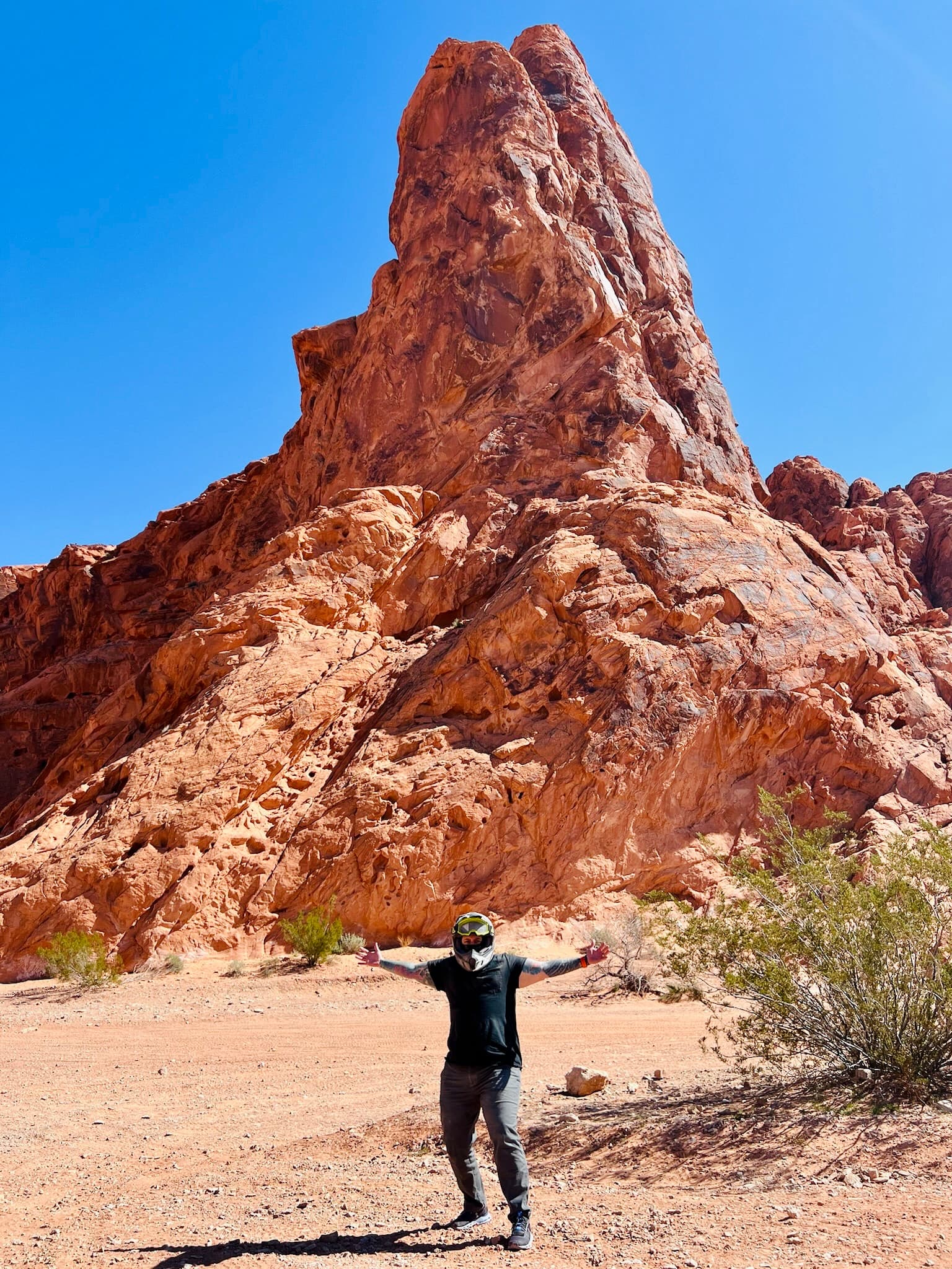 Advisor posing in front of a large rock formation in the desert on a sunny day.
