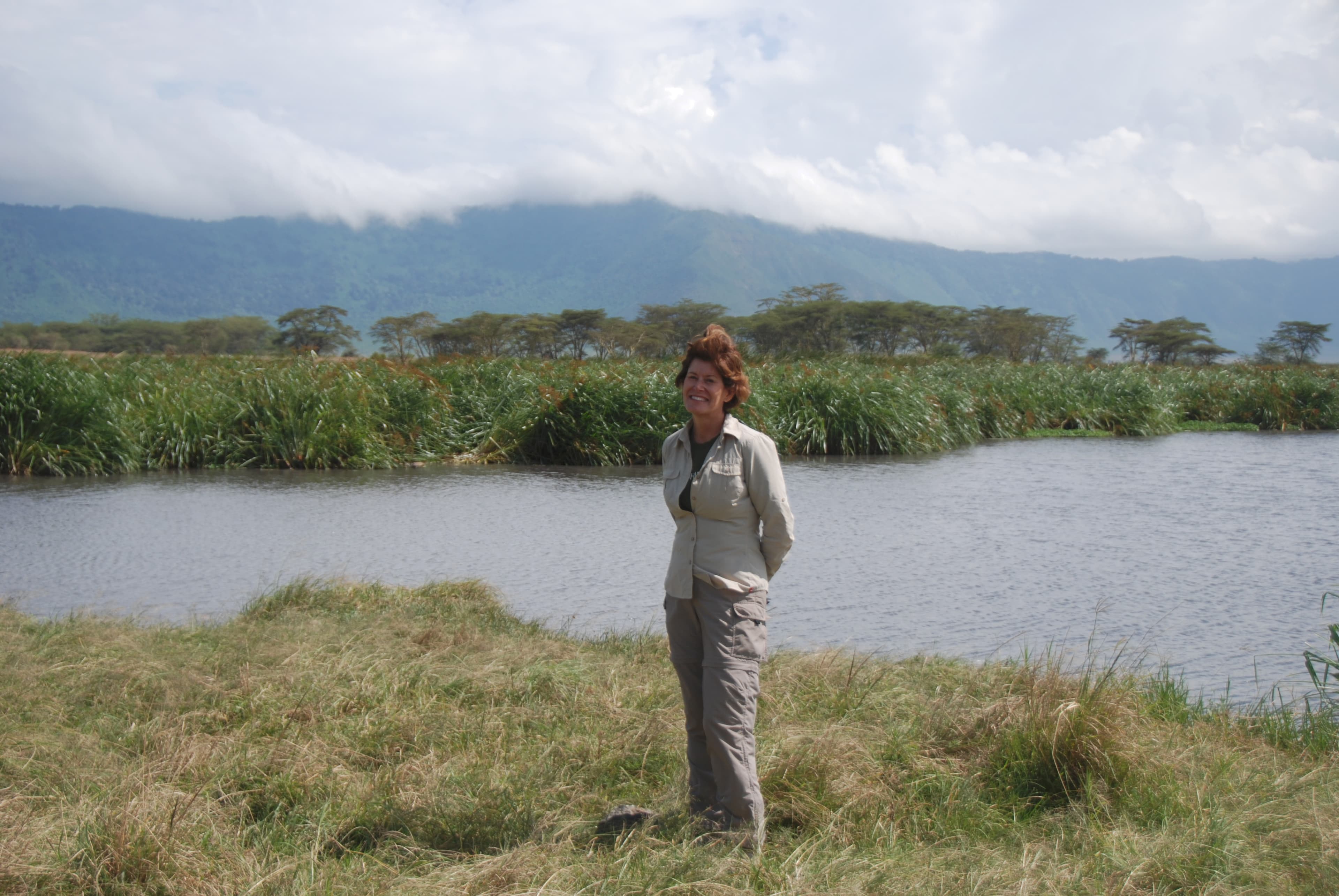 Nancy standing on the banks of a river with a mountain in the background.