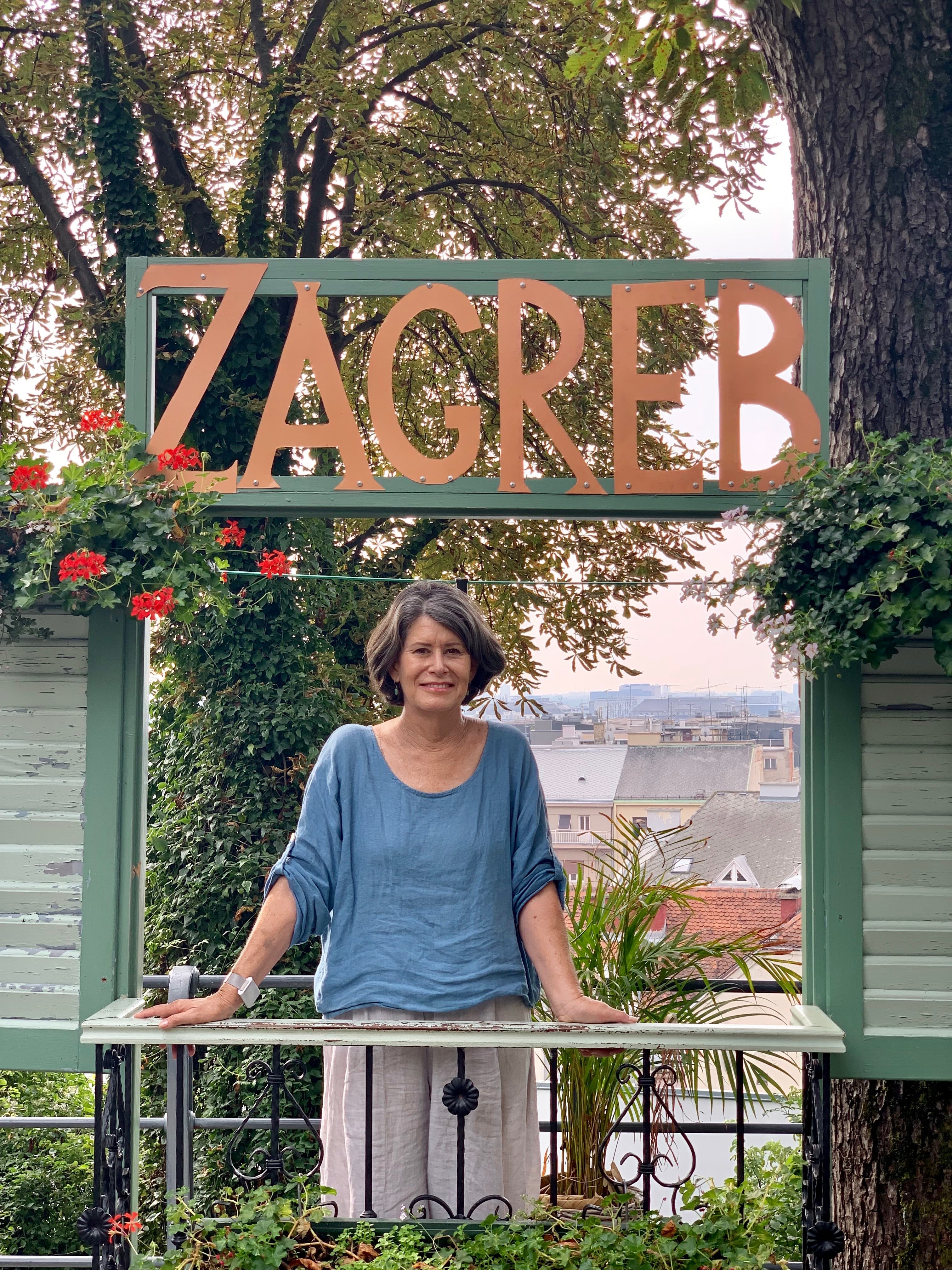 Nancy standing on a balcony with a "Zagreb" sign overhead.