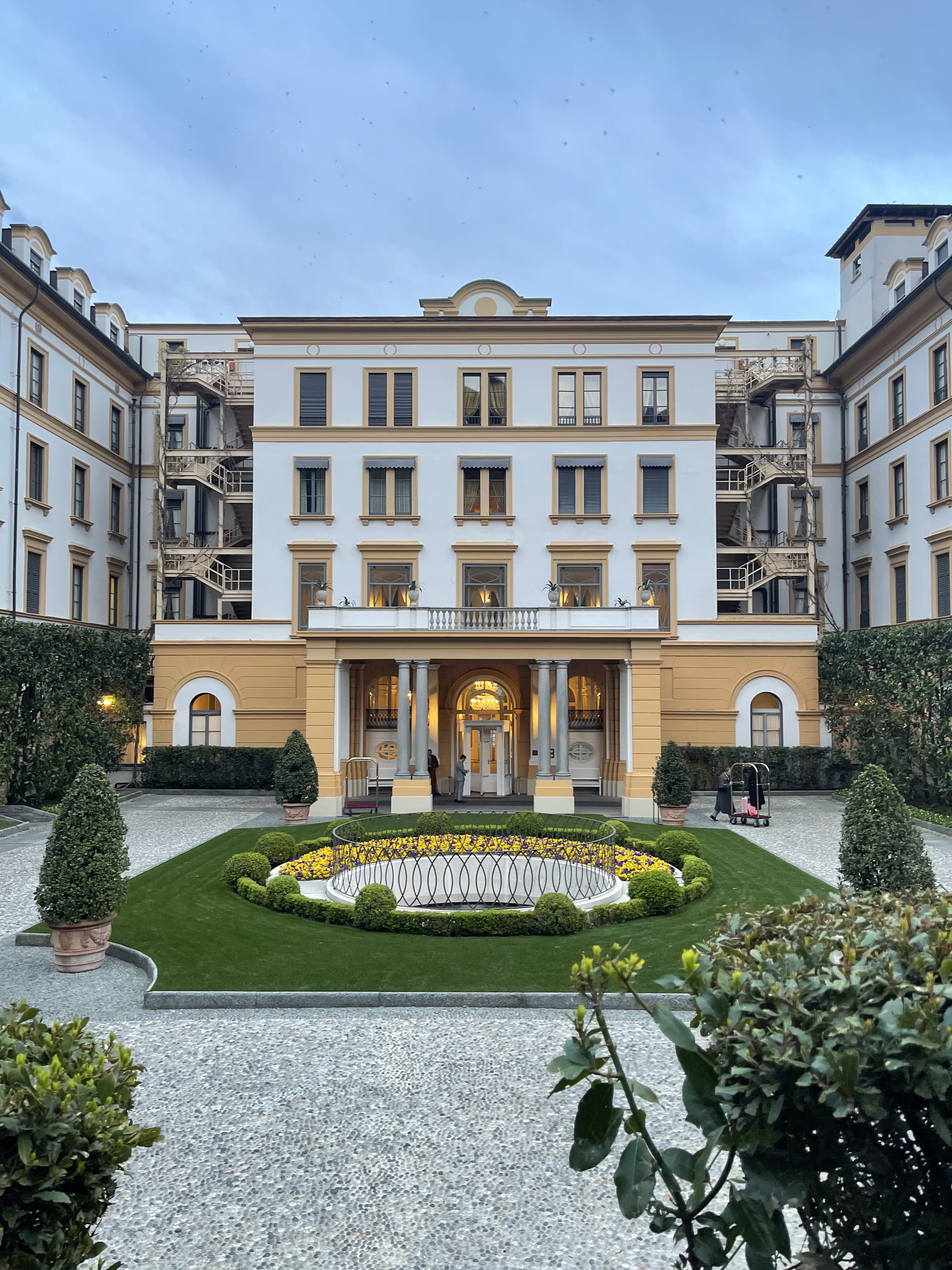 Courtyard with greenery in the center of a white and beige hotel.