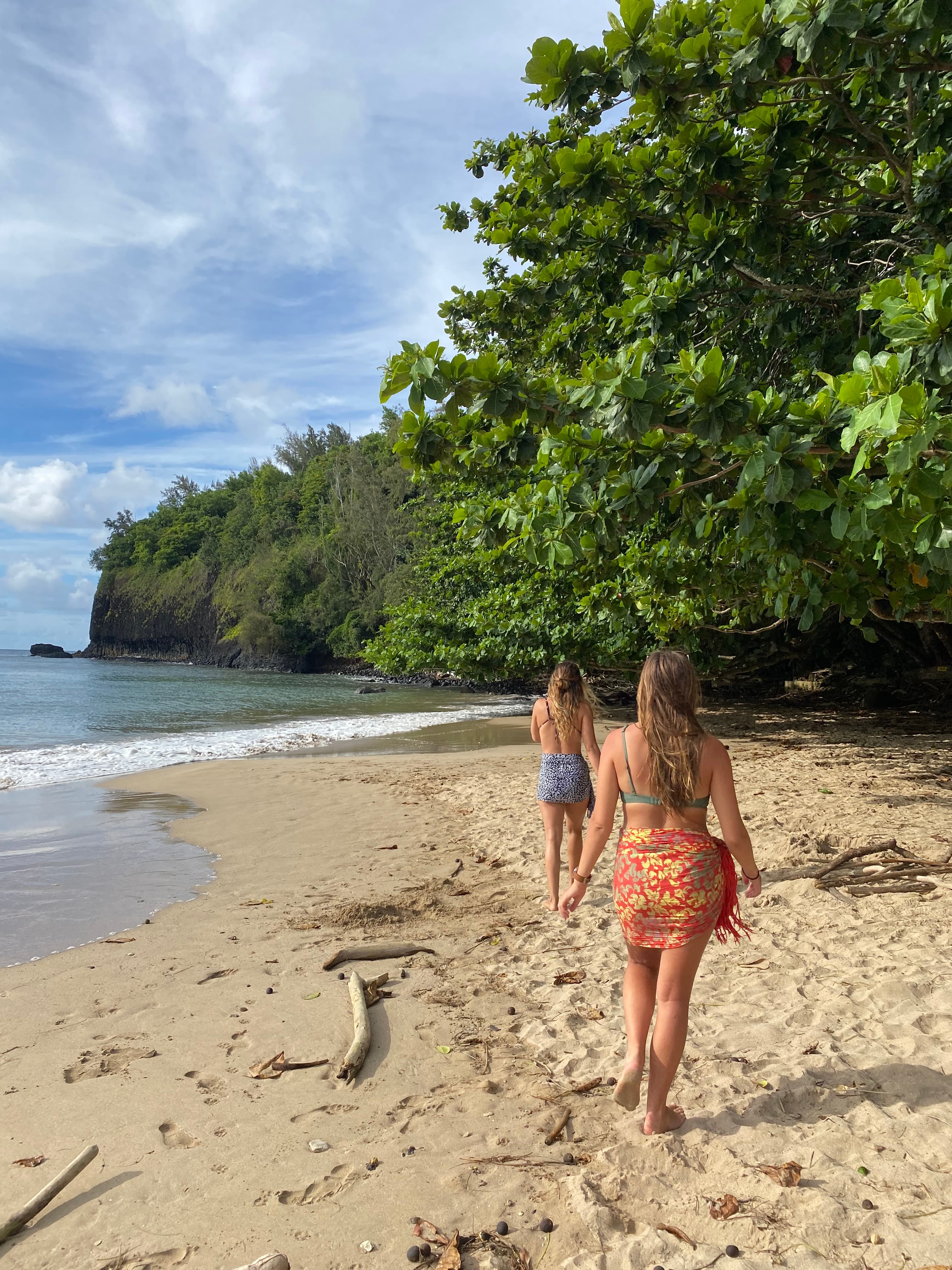 Advisor walking on a sandy beach with the ocean and a jungle in the distance on a sunny day.