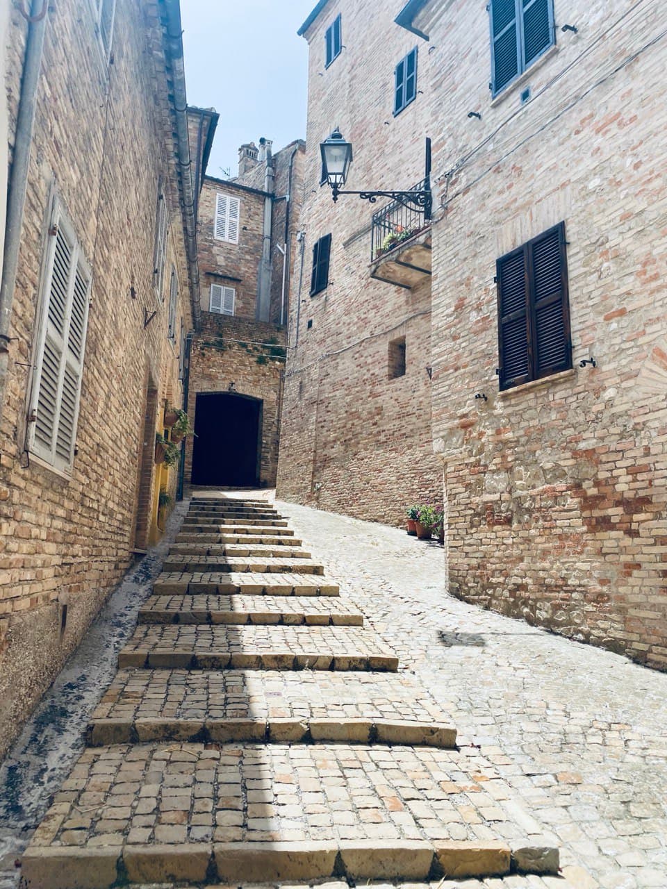 View of an empty stone path between stone buildings on a sunny day