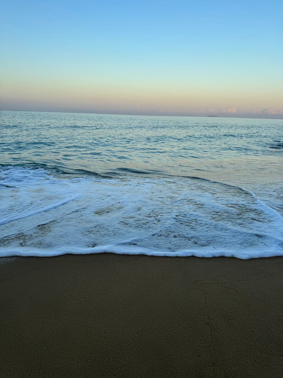 View of small waves on an empty shore at sunset