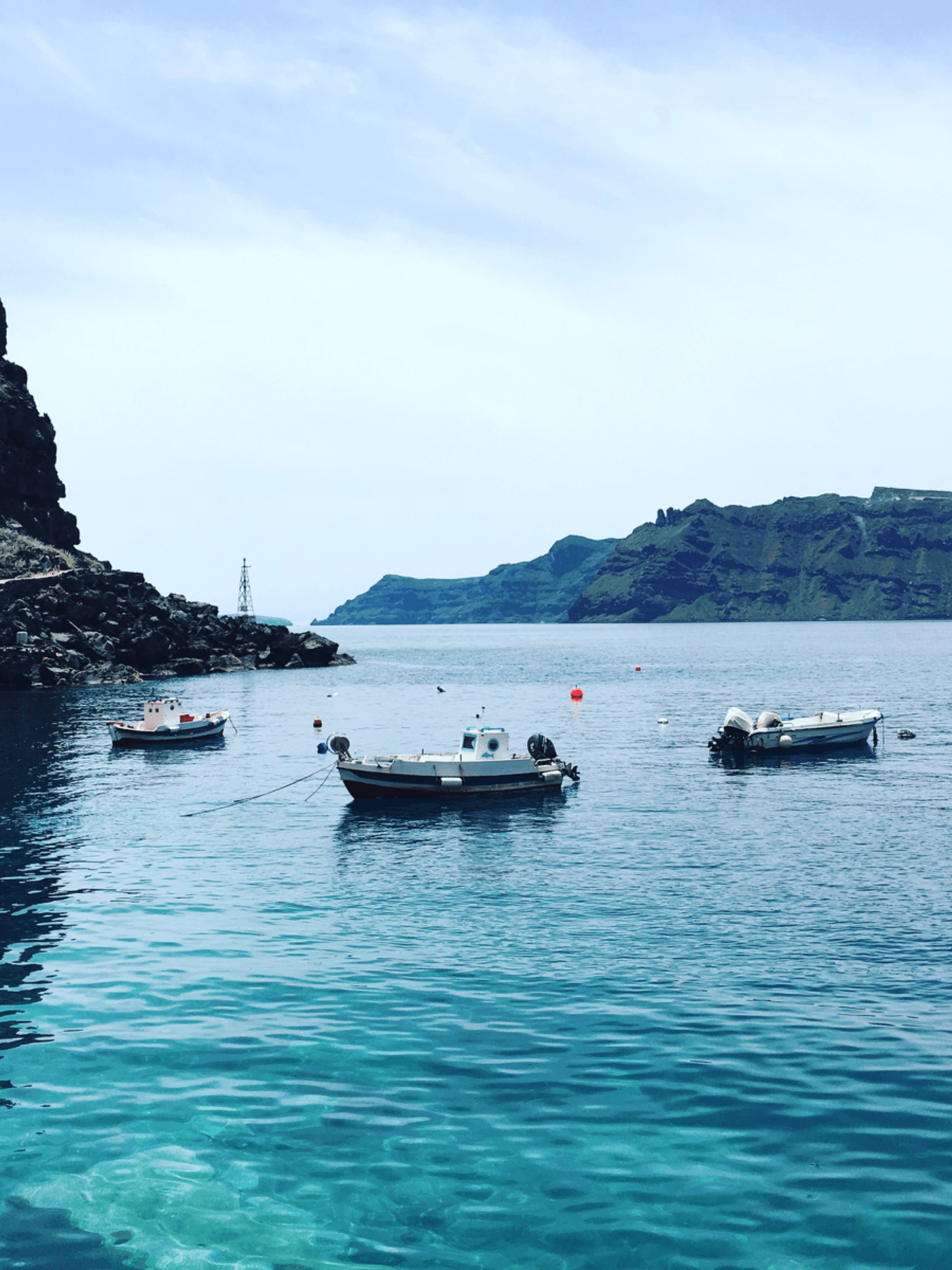 Boats parked in a bay with turquoise blue water and rocky shorelines.