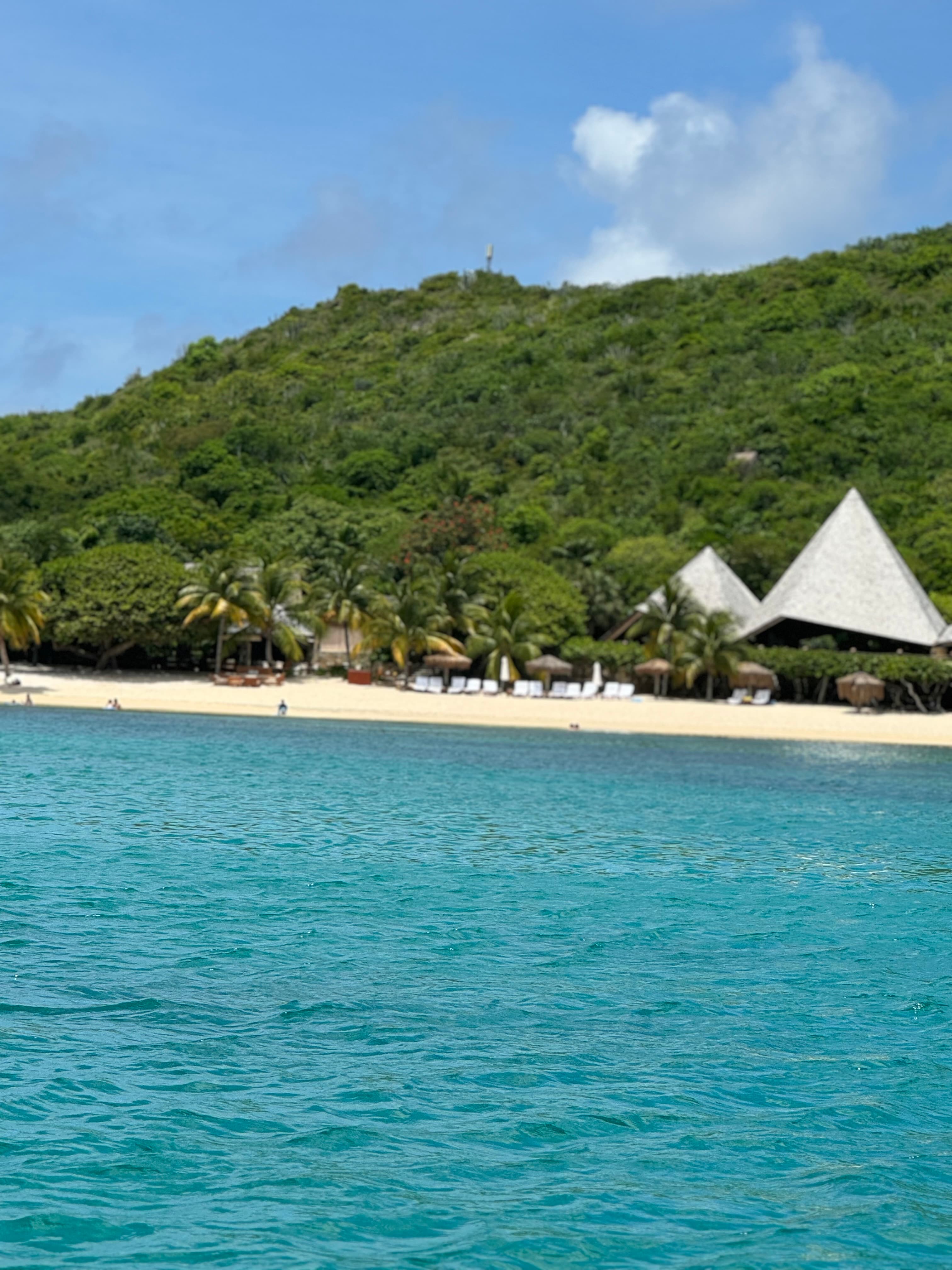 Beautiful view of a turquoise sea and beyond a clean white sand beach with white tents