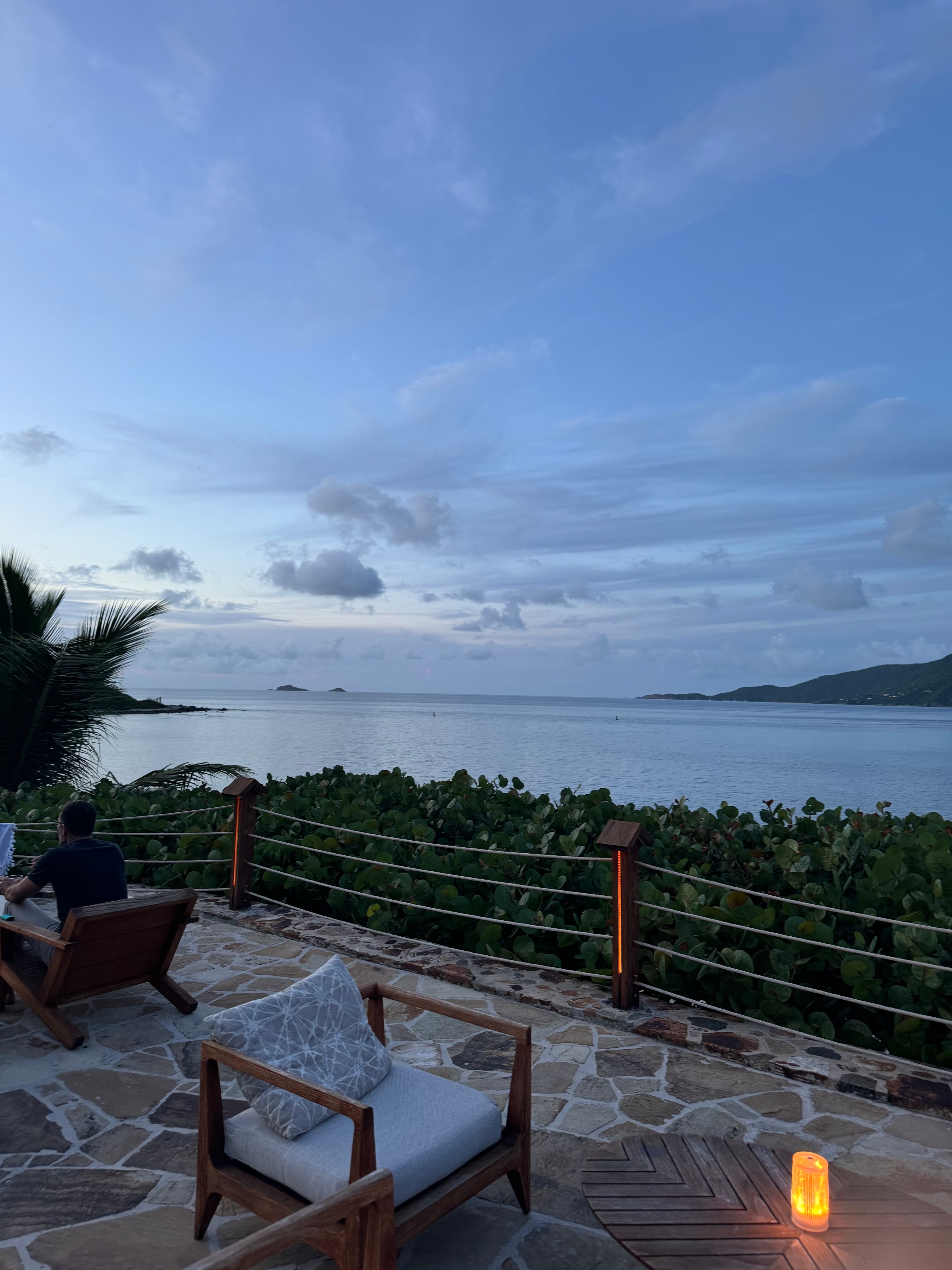 Serene view of a cushioned chair on a patio overlooking the sea at dusk
