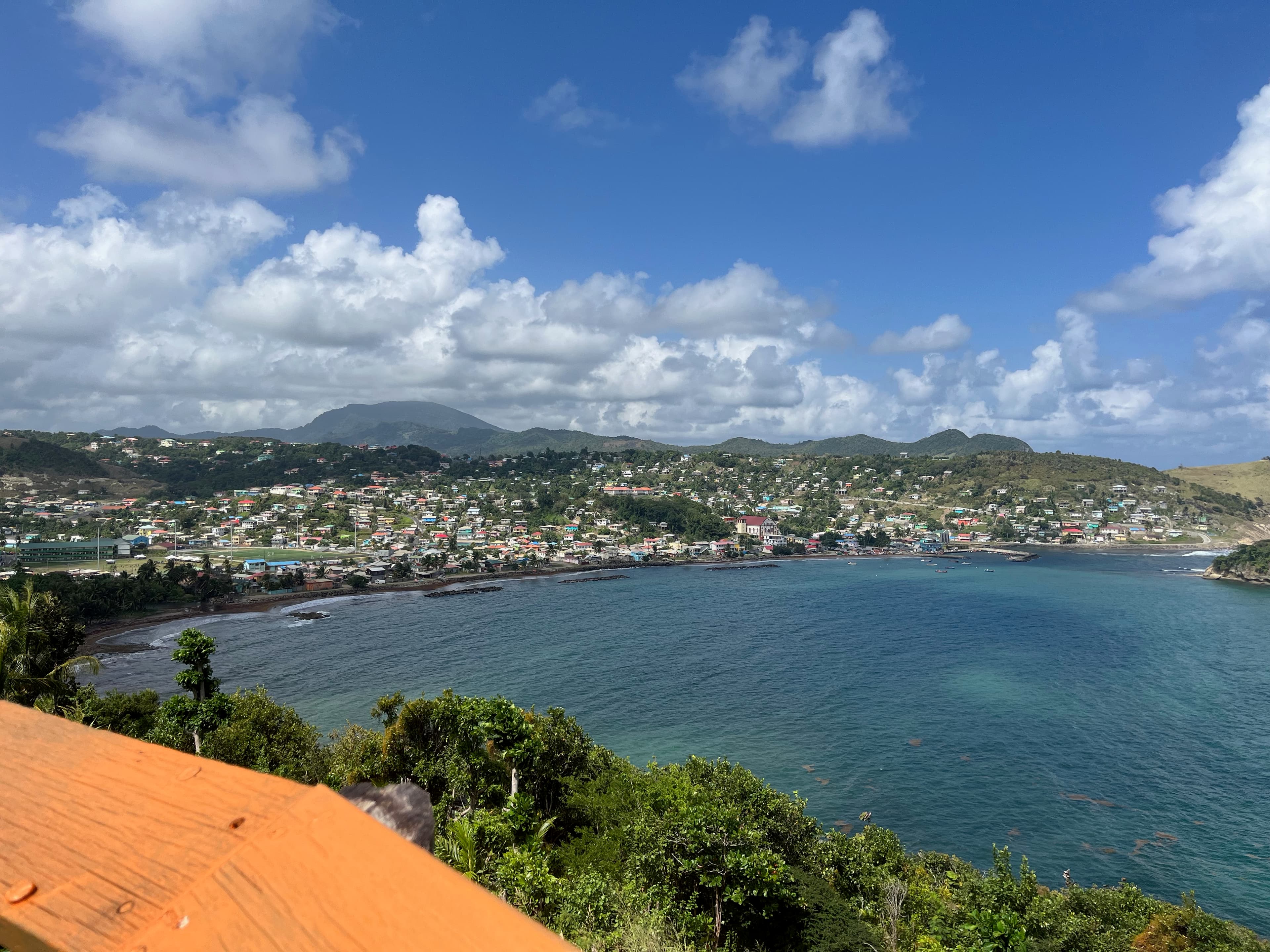 Stunning aerial view of the St. Lucia coastline, with small buildings and a calm bay visible under sunny skies