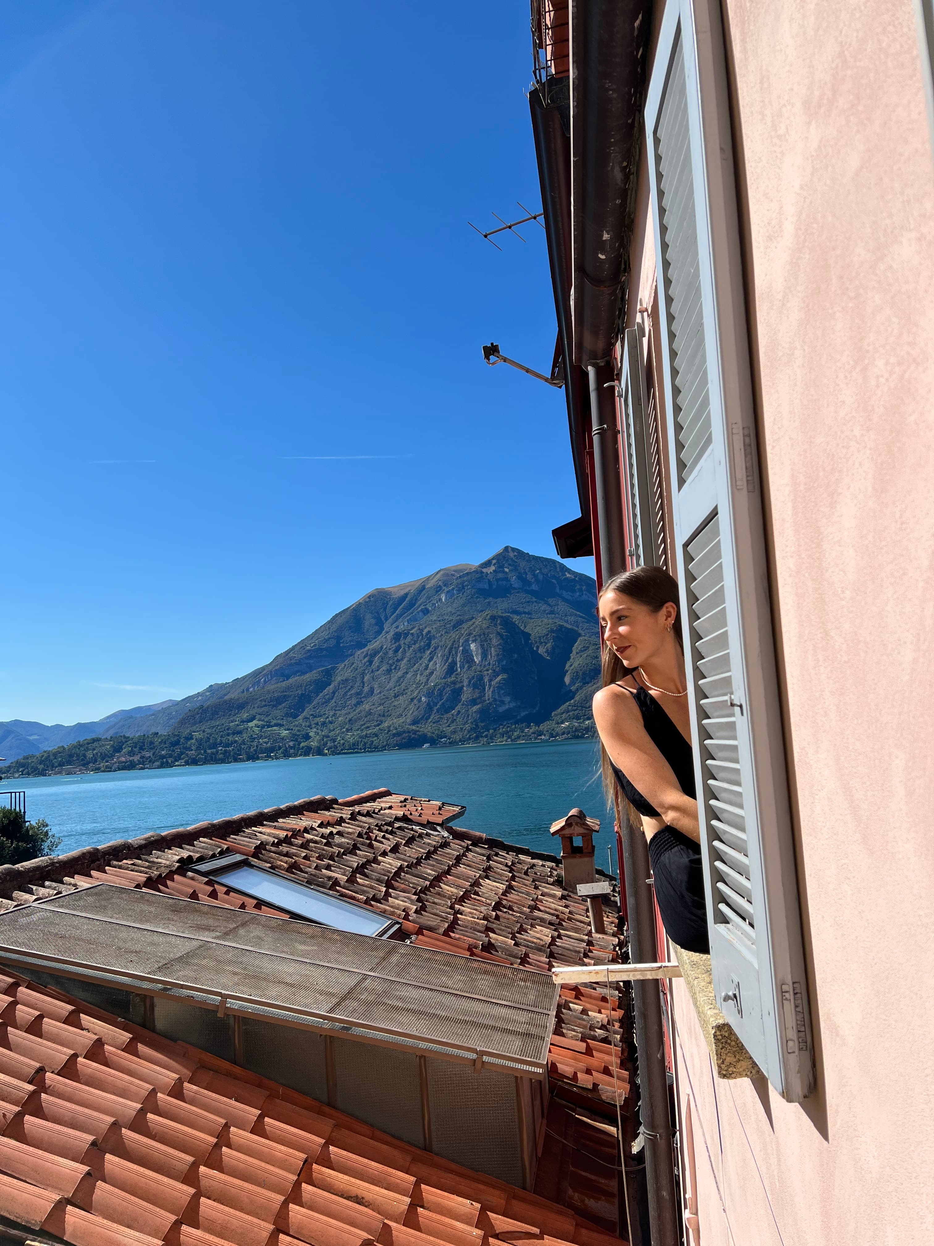 Advisor posing for an image outside of a window with a beautiful view of the ocean in the distance on a sunny day.