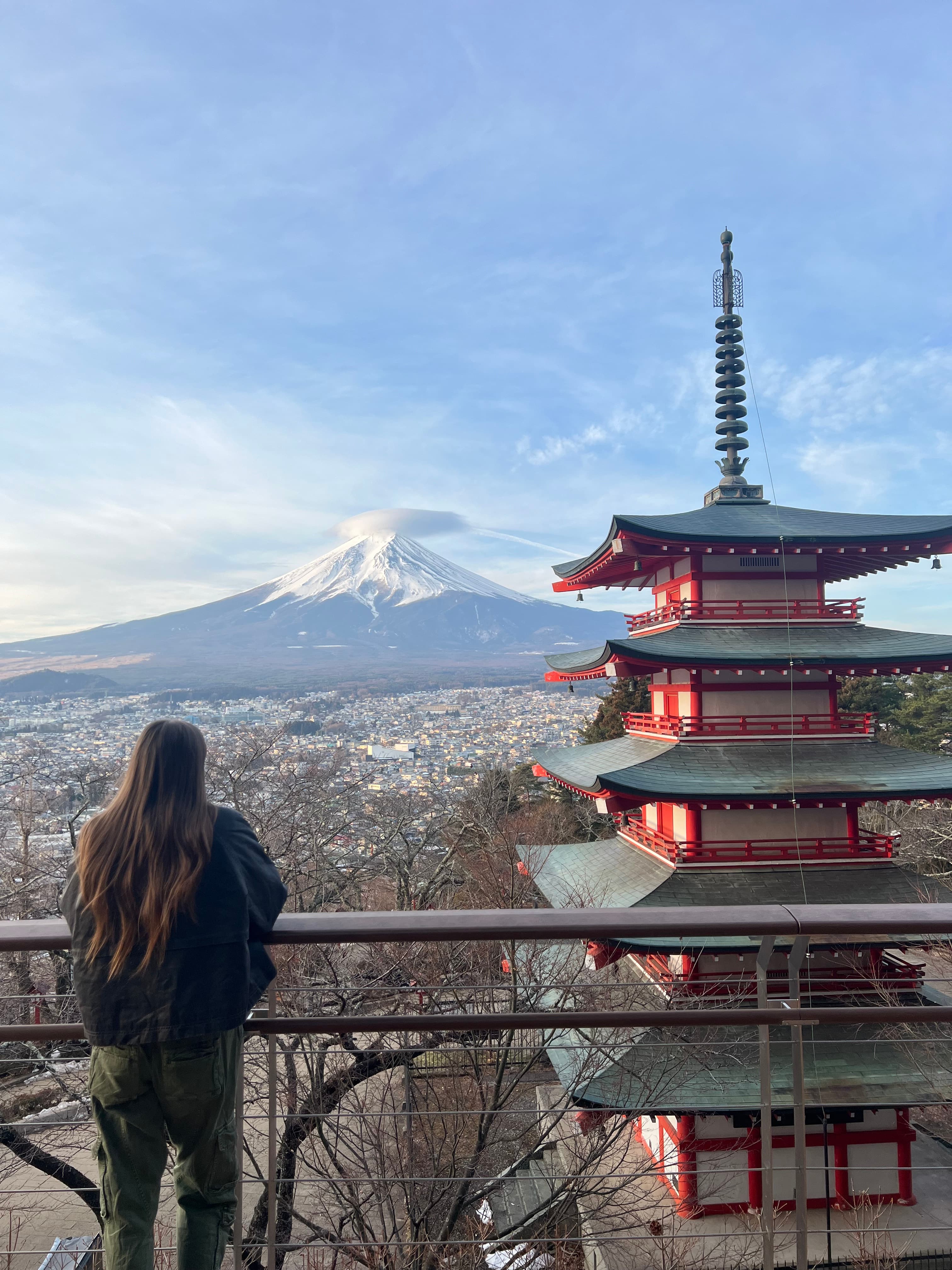 Advisor posing for an image on a balcony that has a temple and snow covered mountains in the distance.