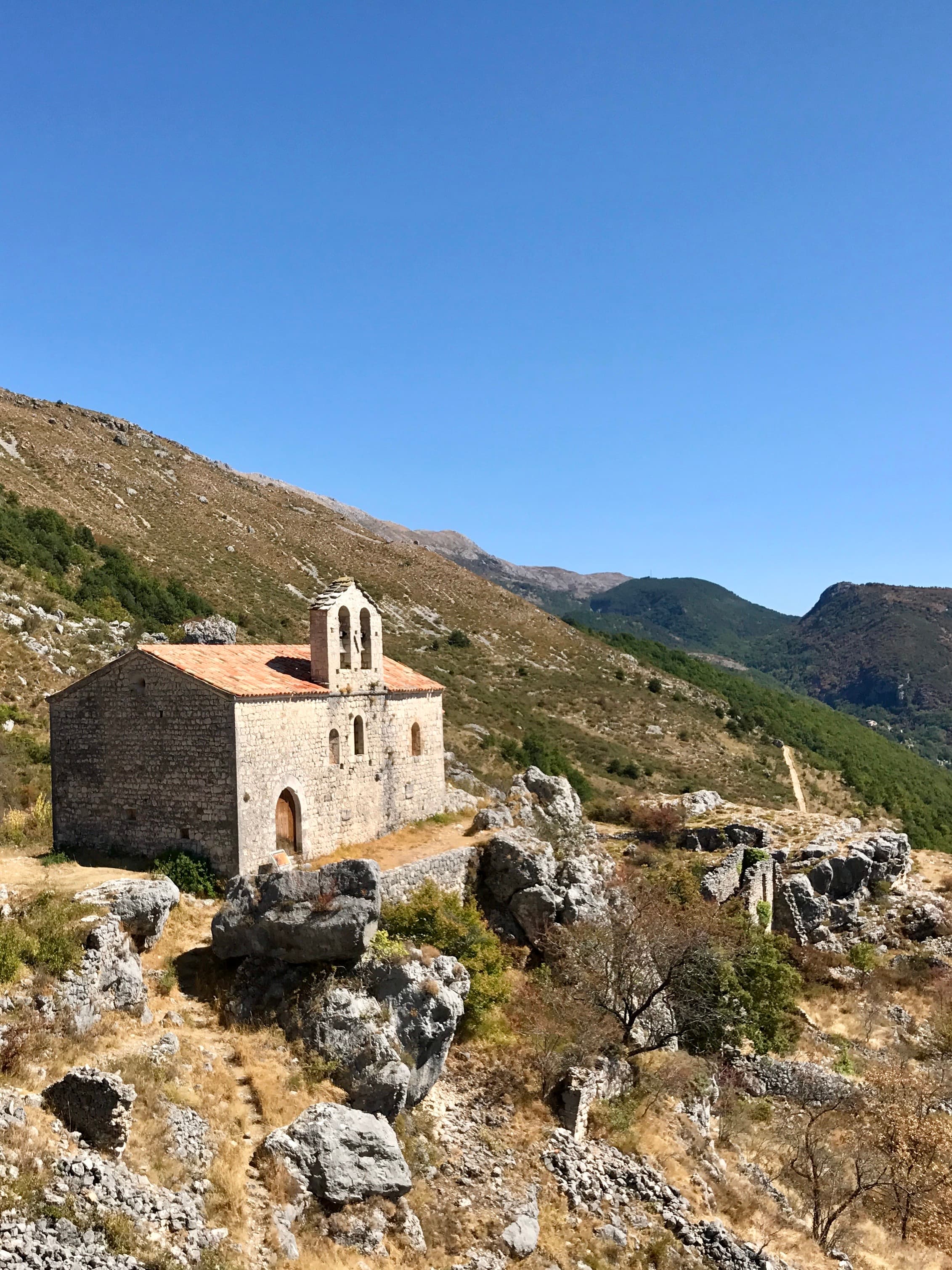 View of an old stone building standing solitary on a rocky hillside on a sunny day