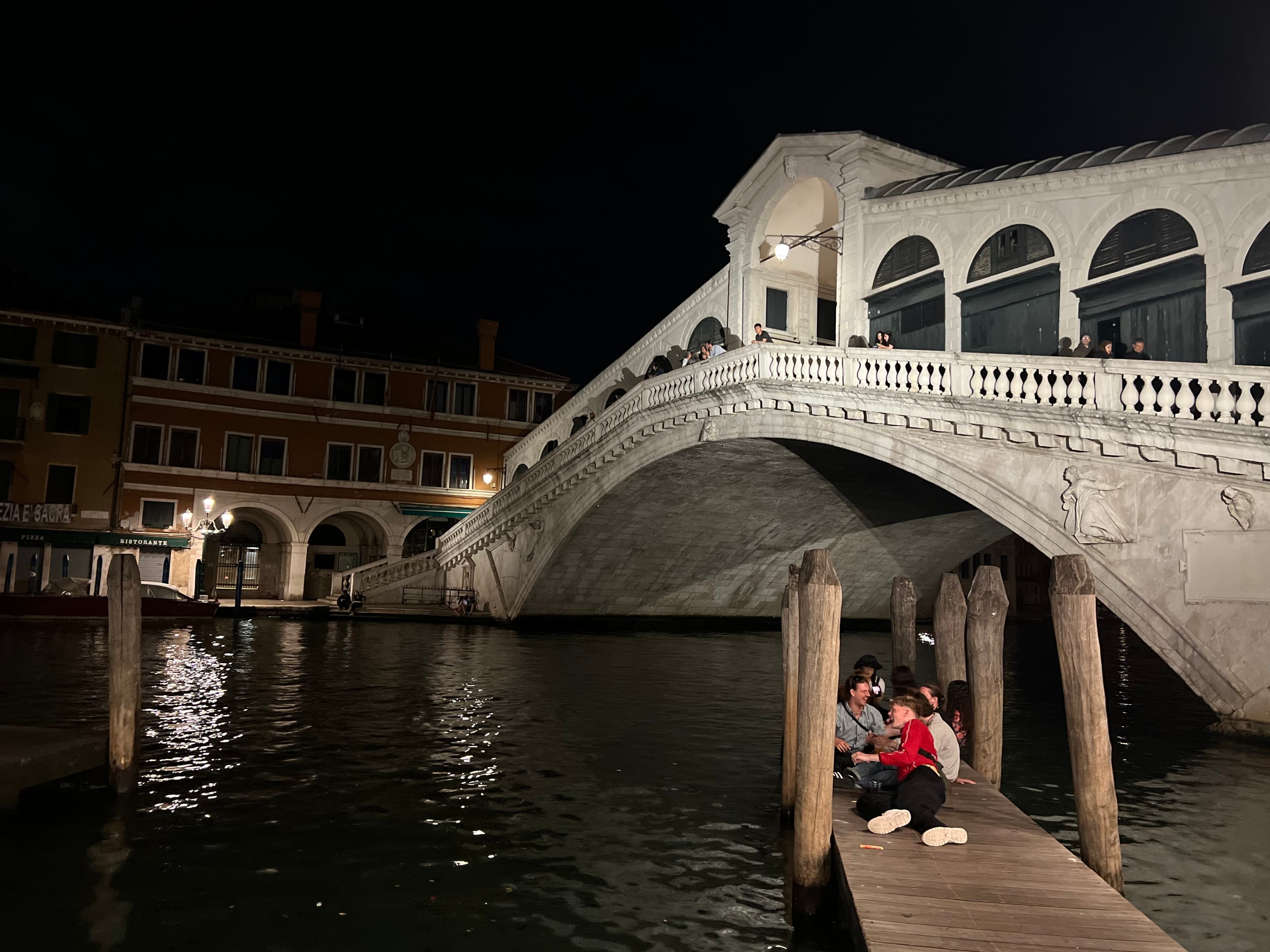 View of a bridge in Venice above a small wooden dock at night