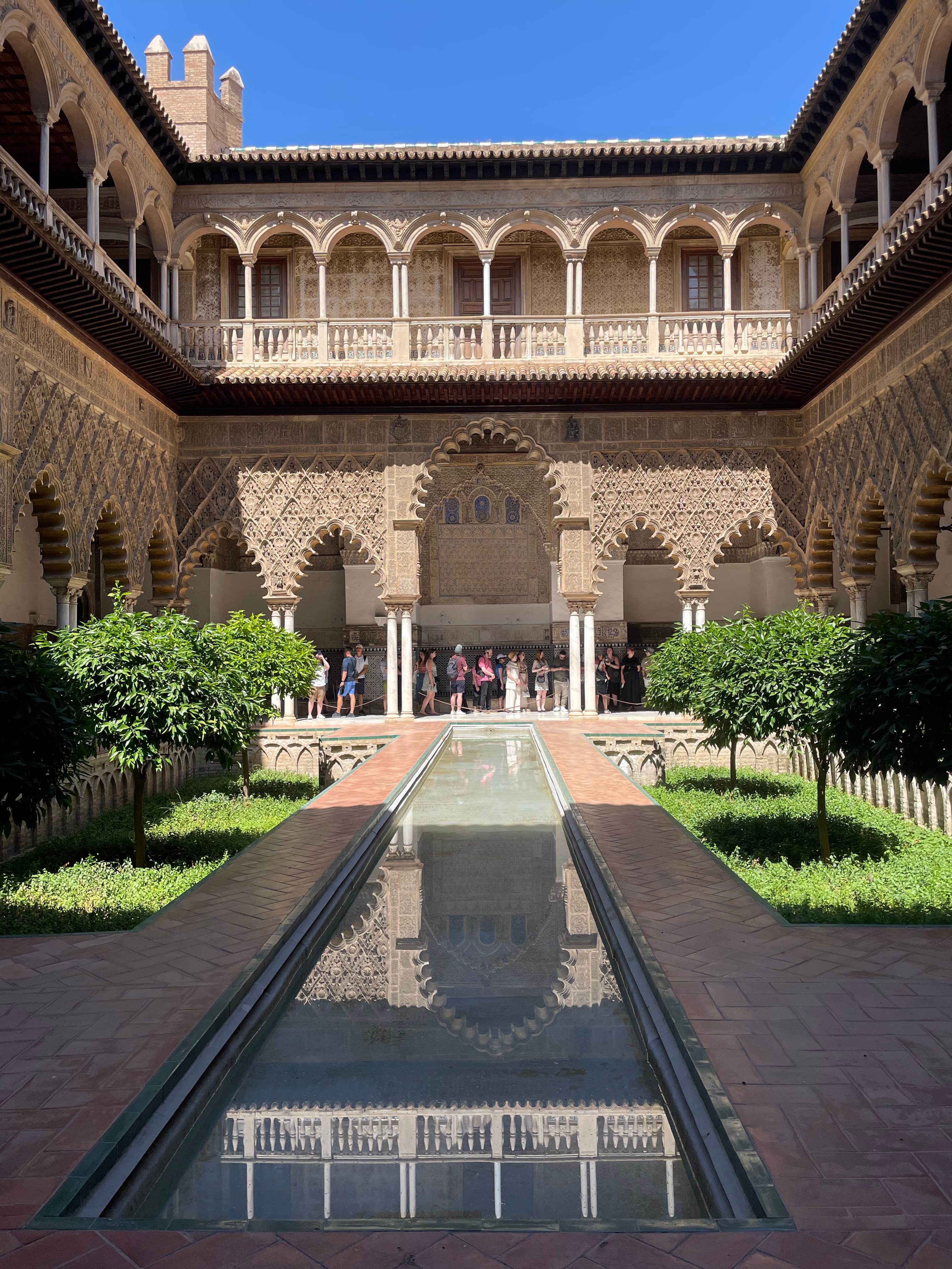 An image of an outside pond with beautiful archways and foliage surrounding the balconies during the day.
