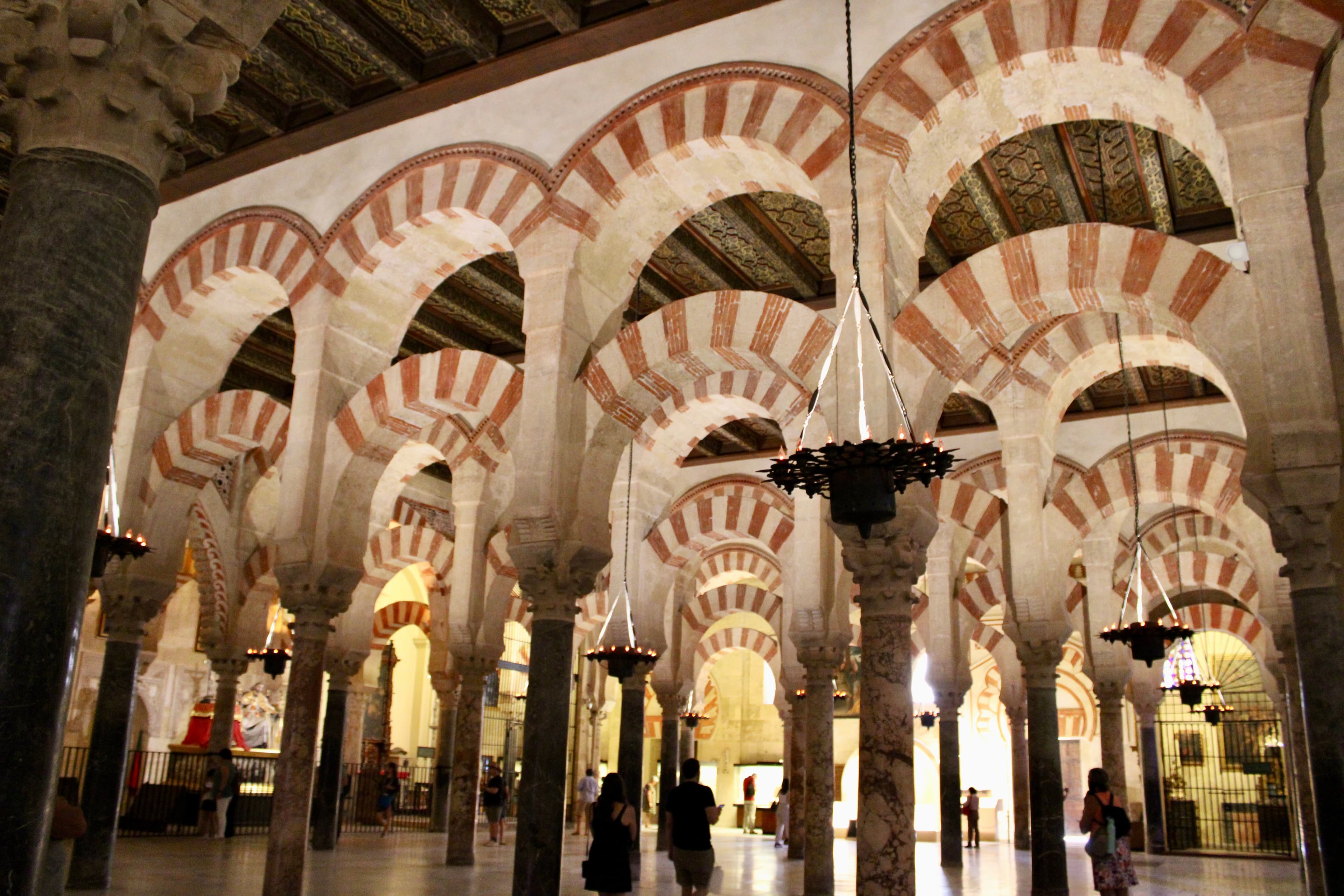 An image of the inside of a beautiful building with pillars and archways during the daytime.