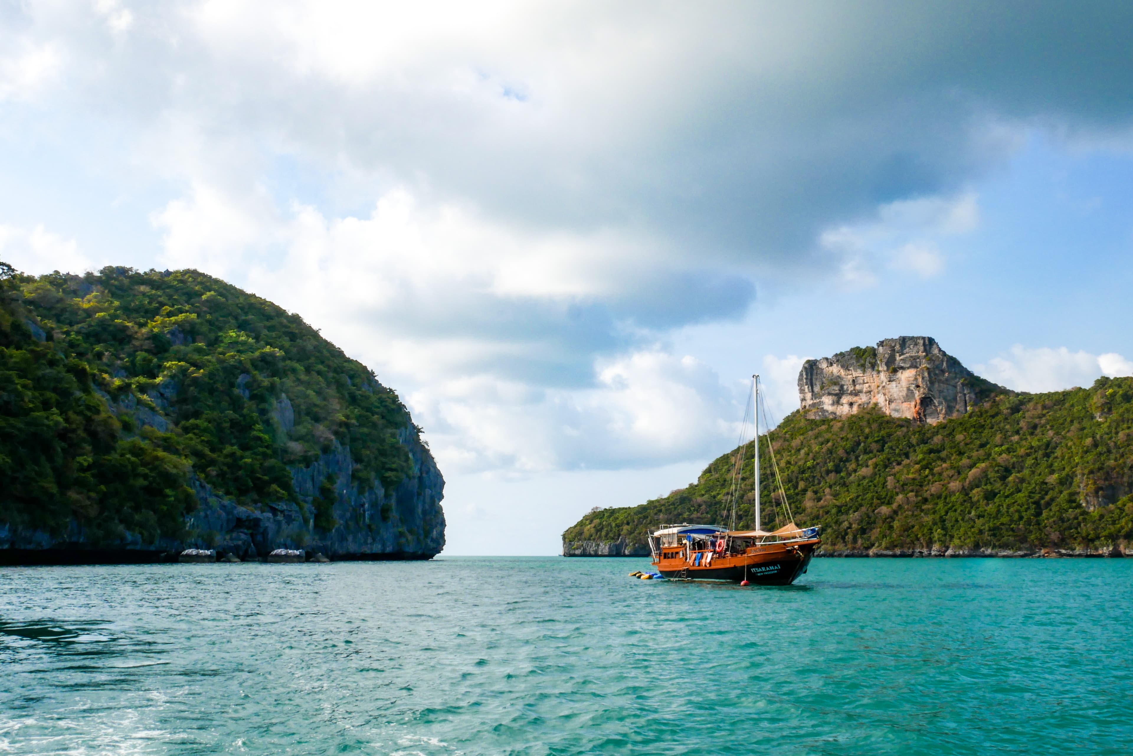 A view of the ocean with rock formations in the distance and a boat in the water.