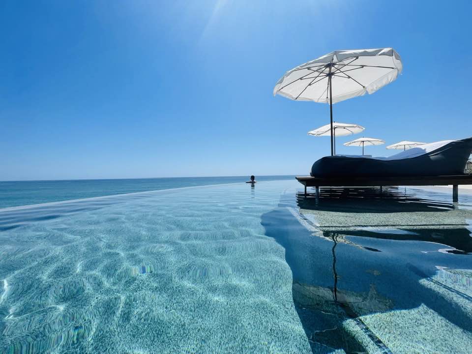 A view of a luxury pool with loungers and umbrellas for shade on a sunny day.