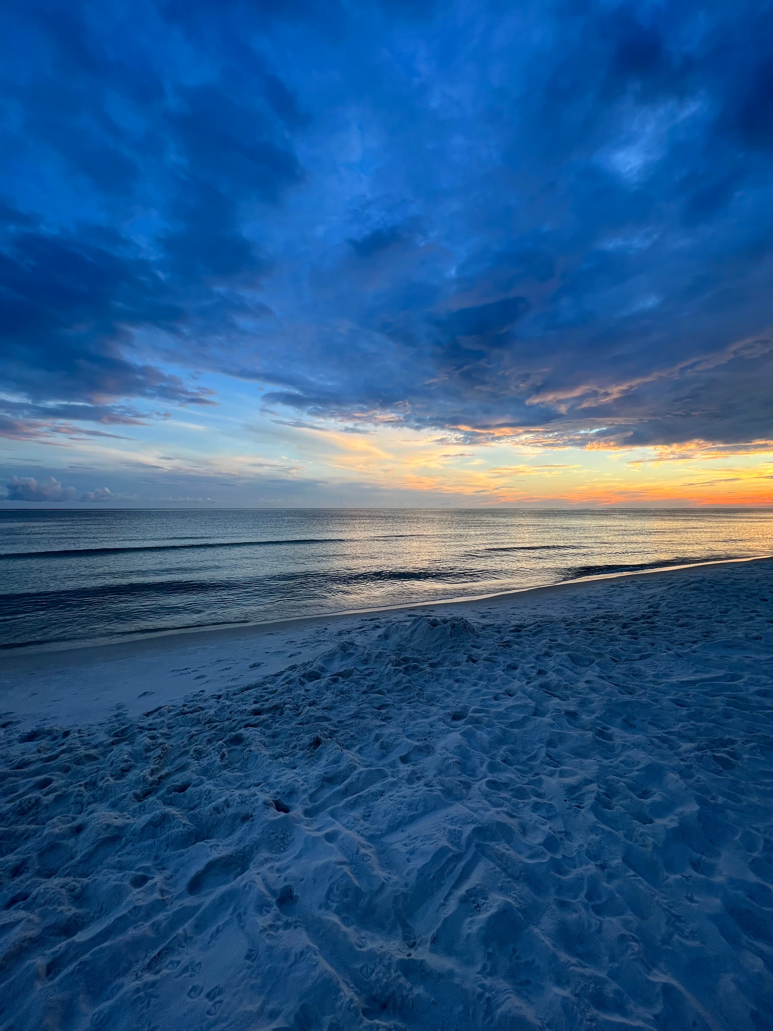 A view of a beautiful blue sunset on the beach with a golden sky.