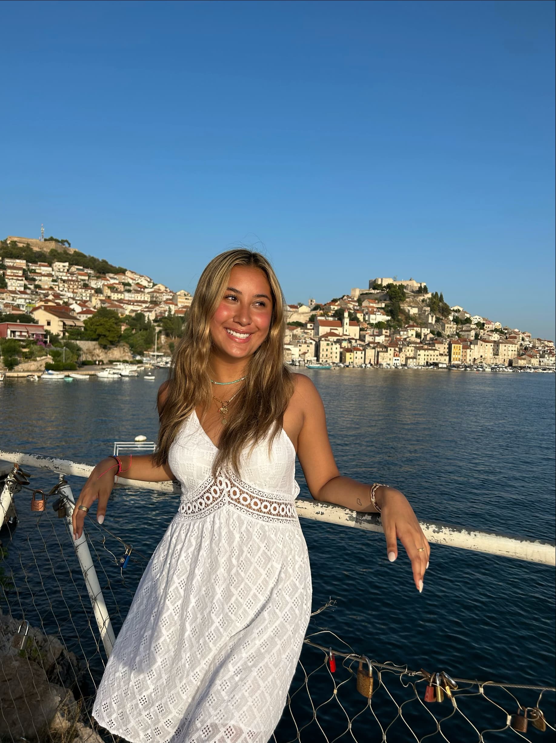 Advisor posing for an image on a boat with a costal town and the ocean in the distance on a sunny day.