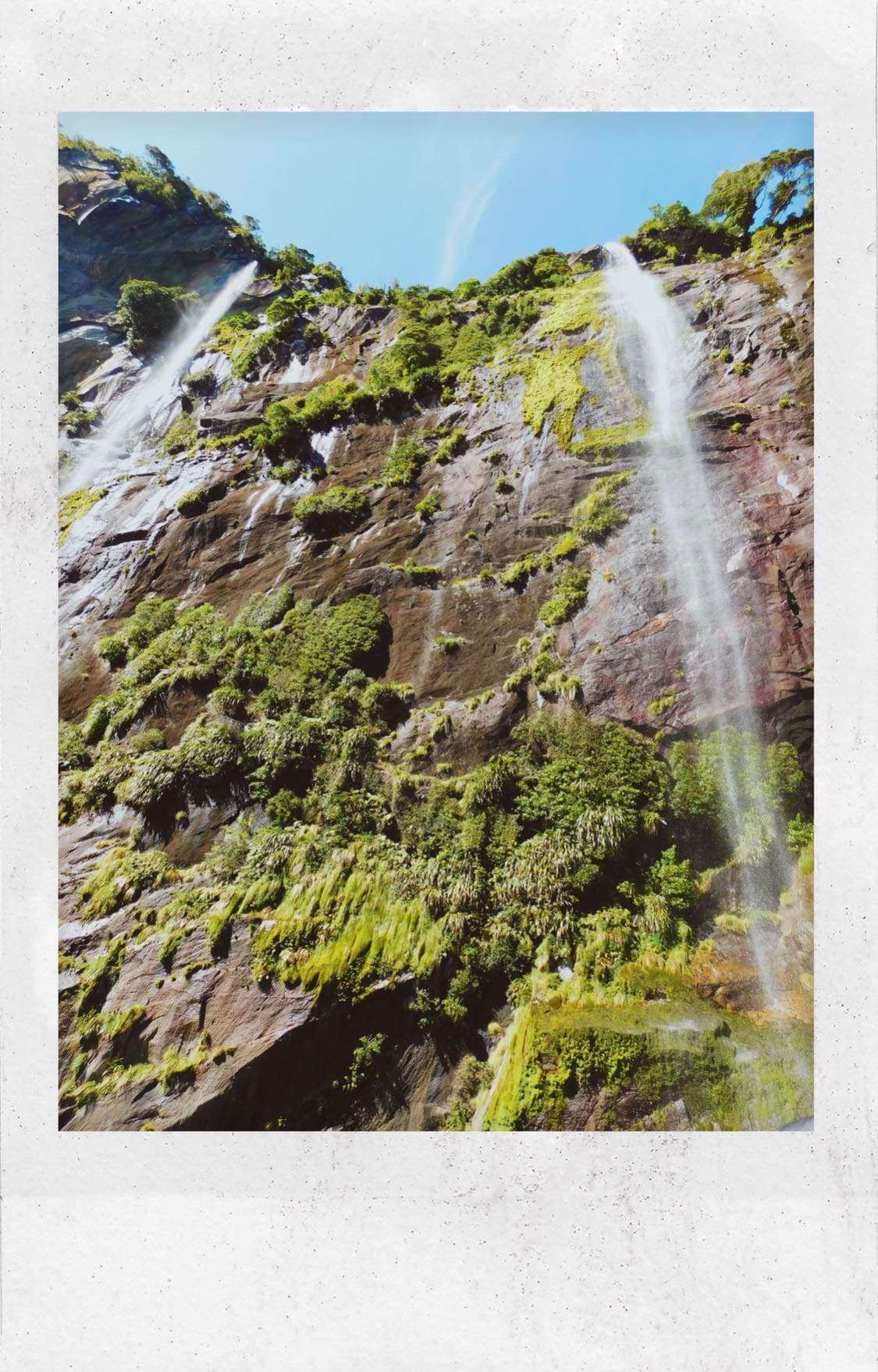 Polaroid photo of a waterfall during the daytime.