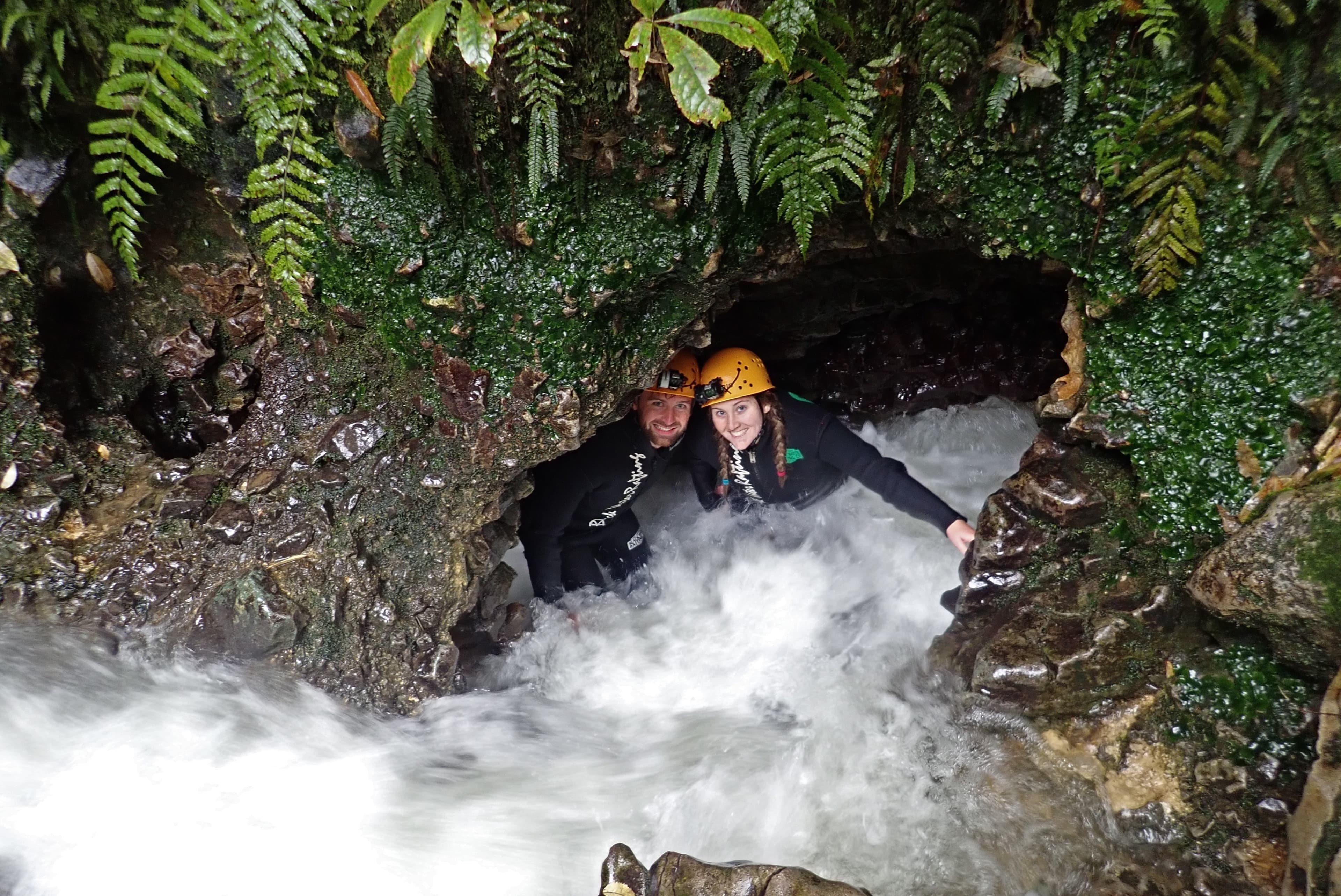 Advisor posing in a cave with rushing water and foliage in the background.