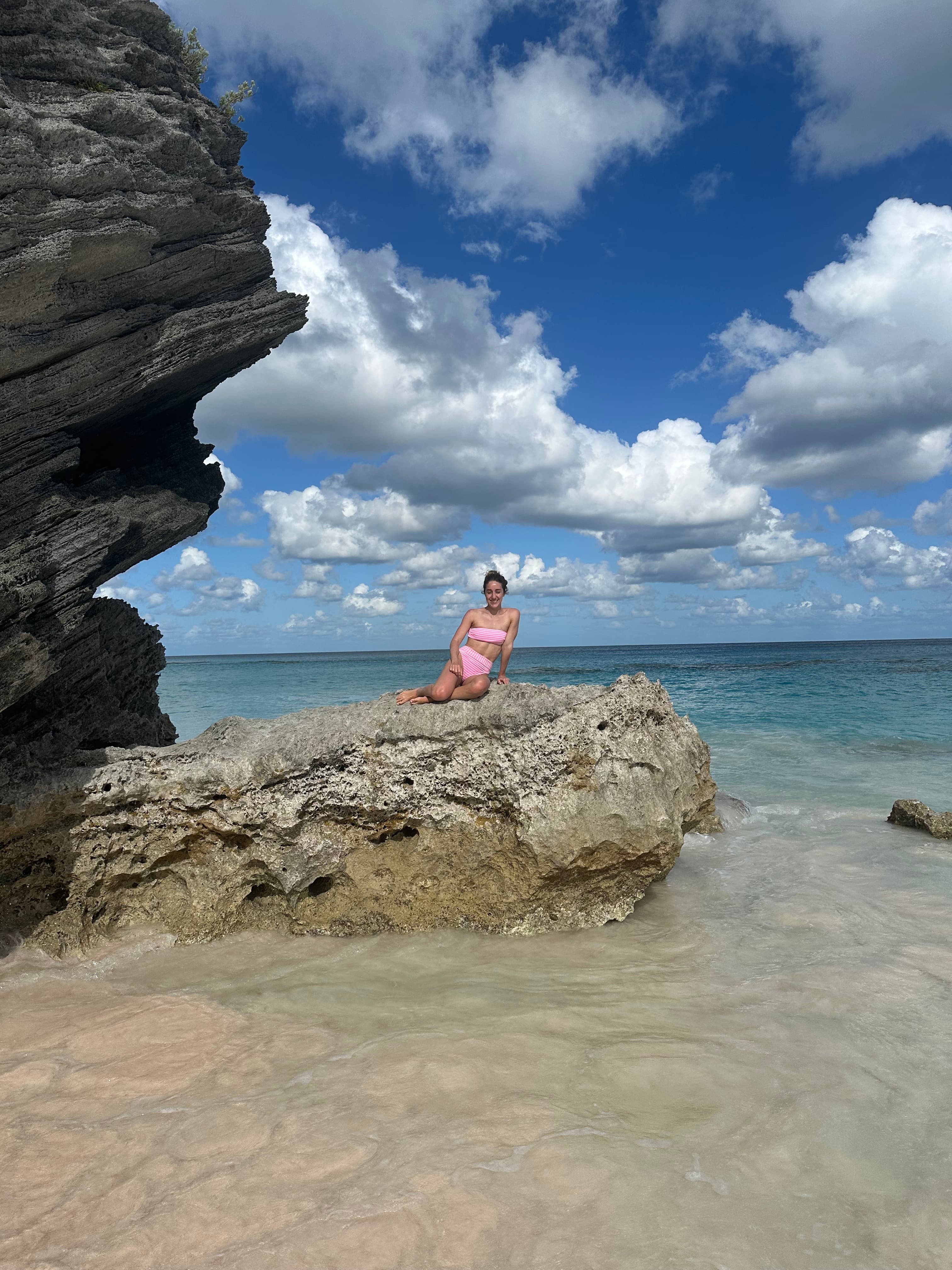 Amanda in a bathing suit posing on a rock in shallow ocean water on a sunny day