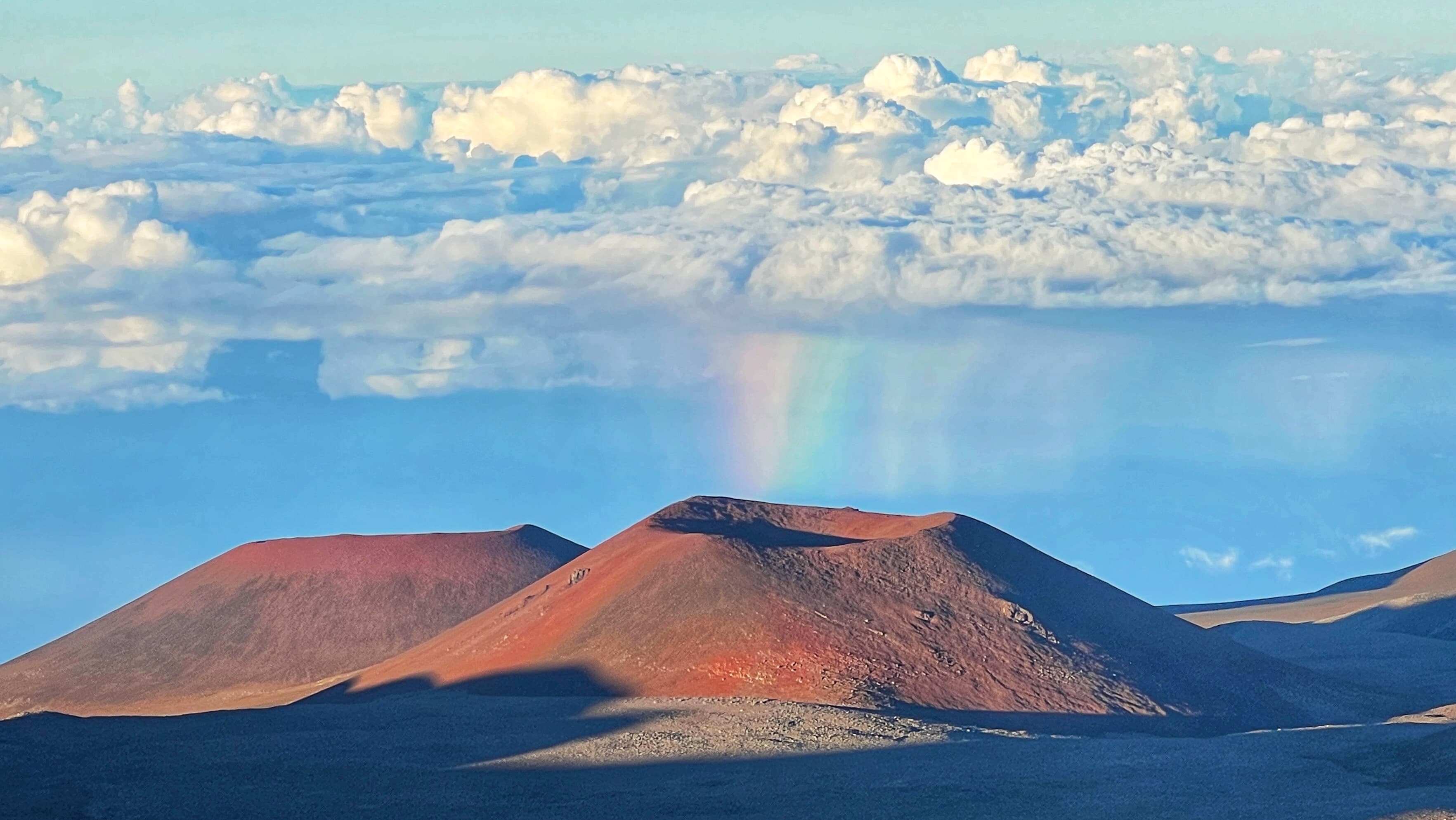 Beautiful view of a volcanic landscape with the appearance of a rainbow emerging from the clouds above