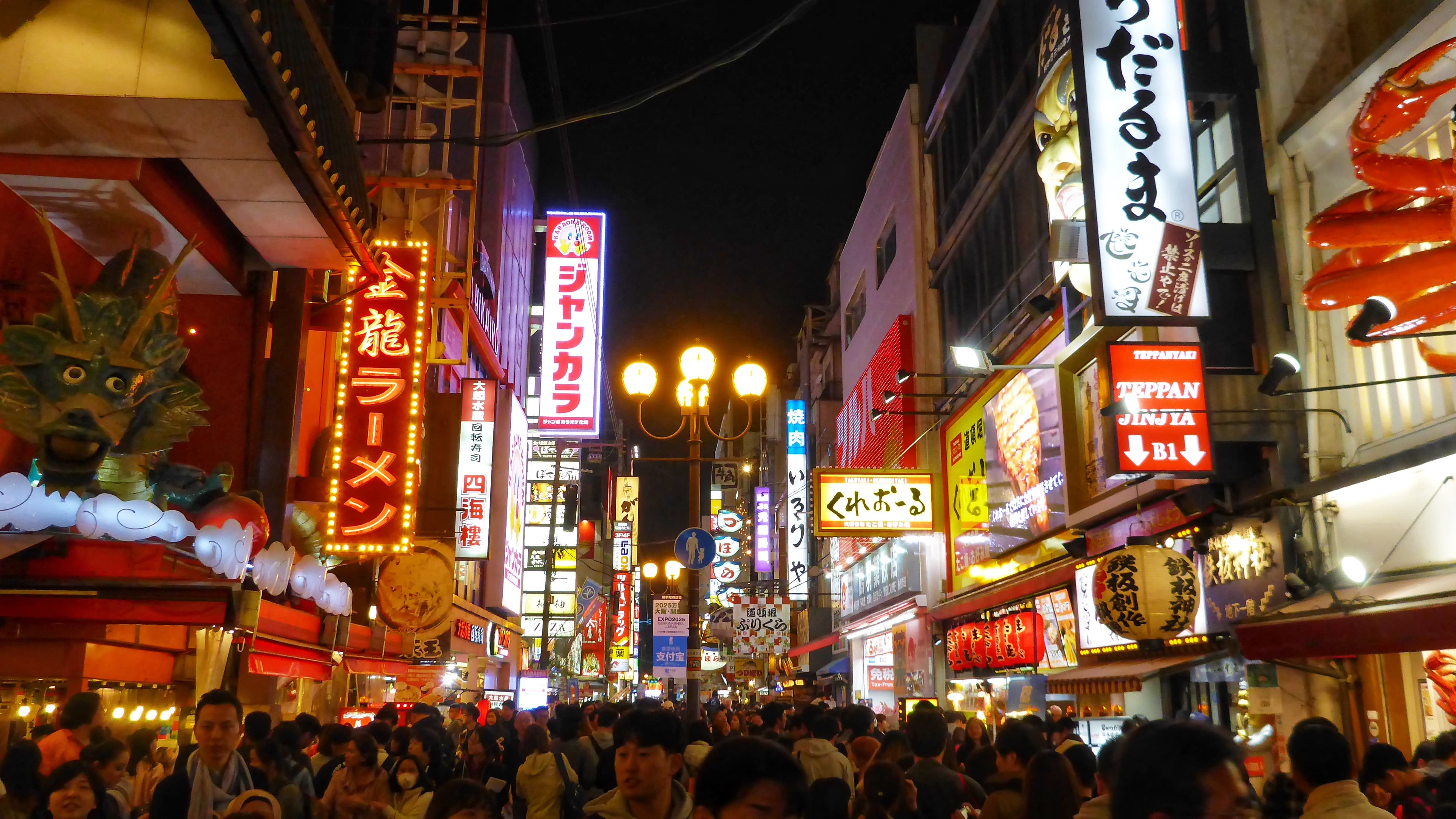 View of a crowded street lit up at night with signs in different colors