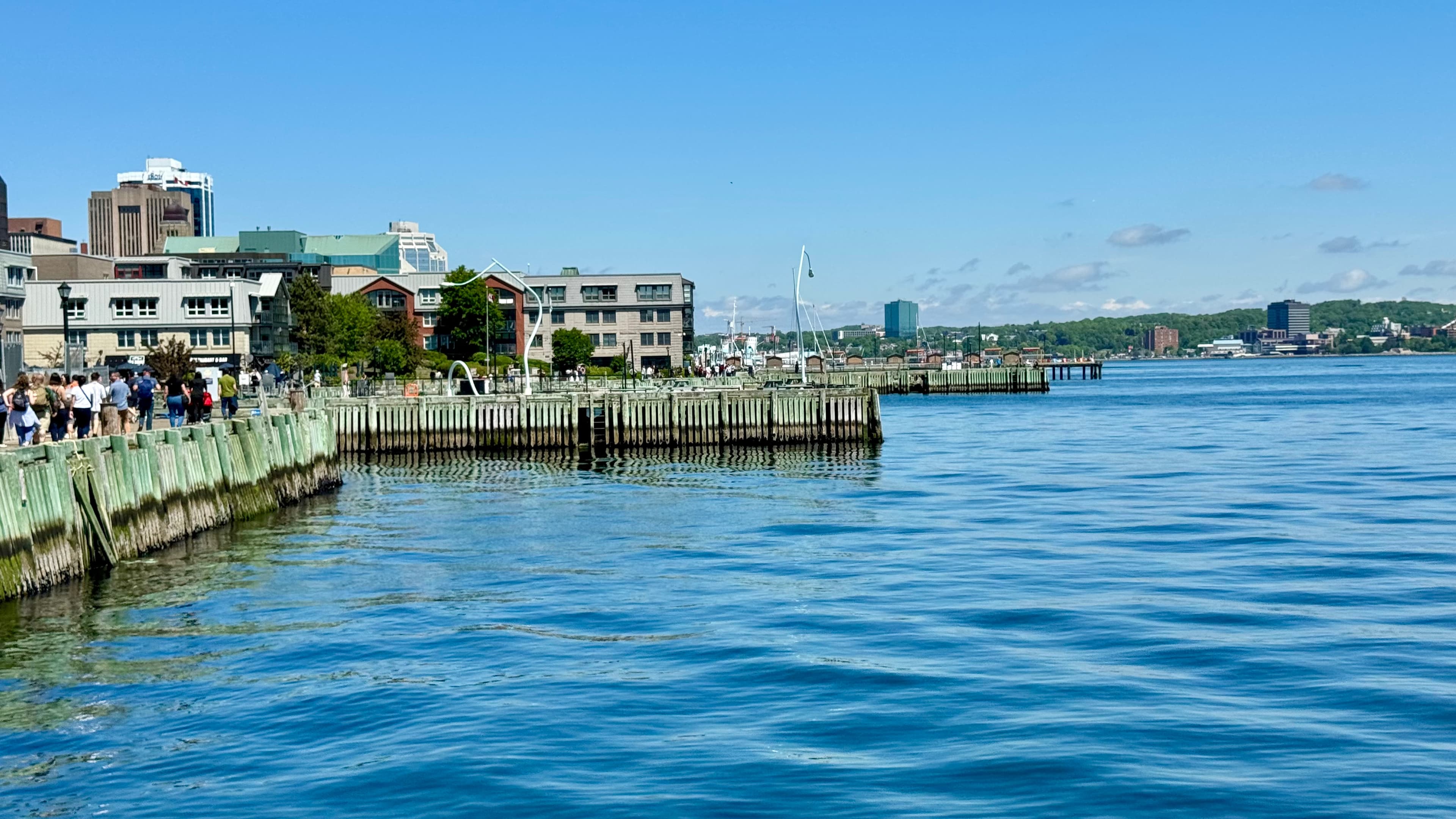 Beautiful view of a sunny waterfront area in Halifax with pedestrians seen along the boardwalk